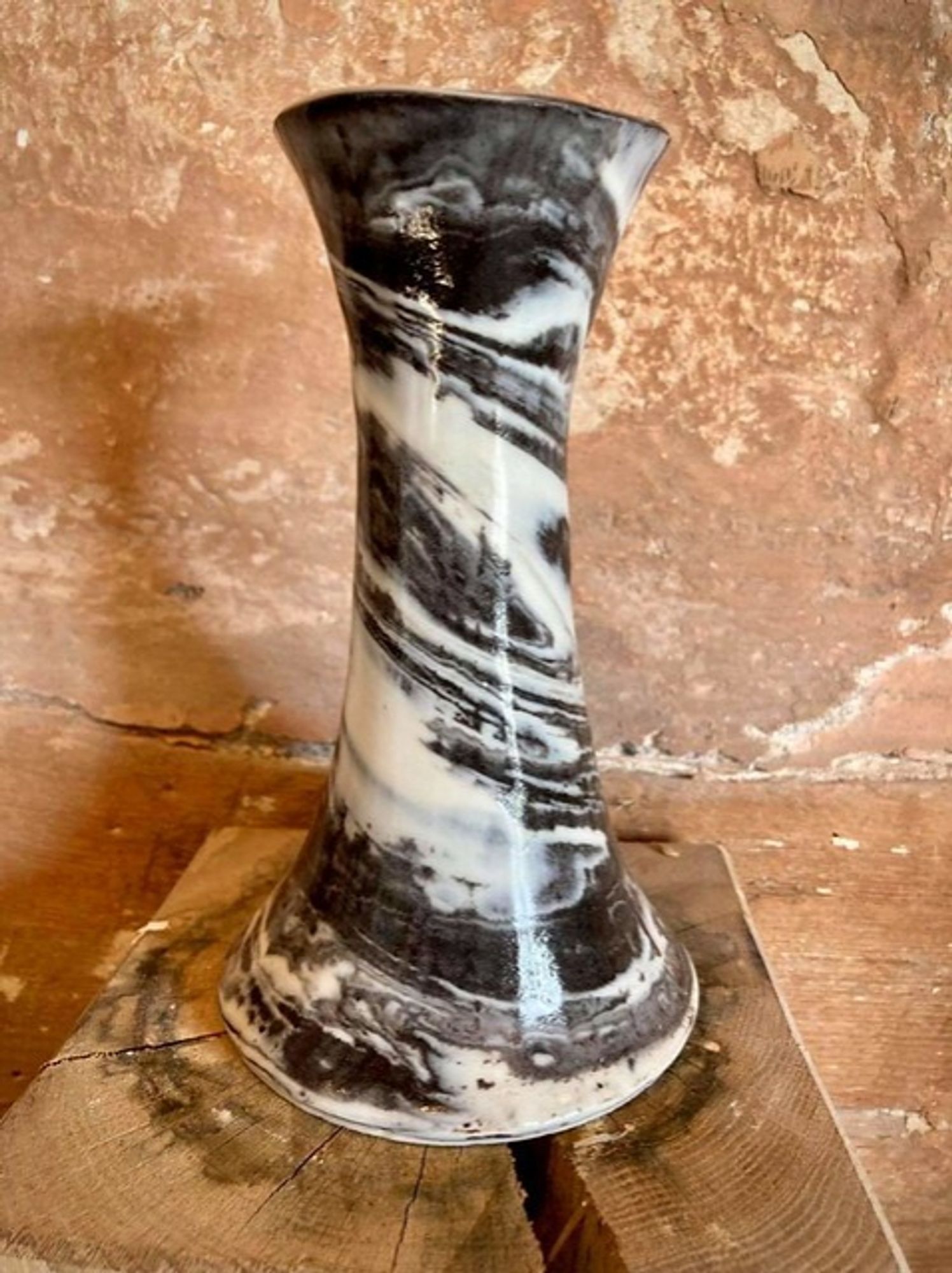 A black and white marbled vase standing on a wooden block