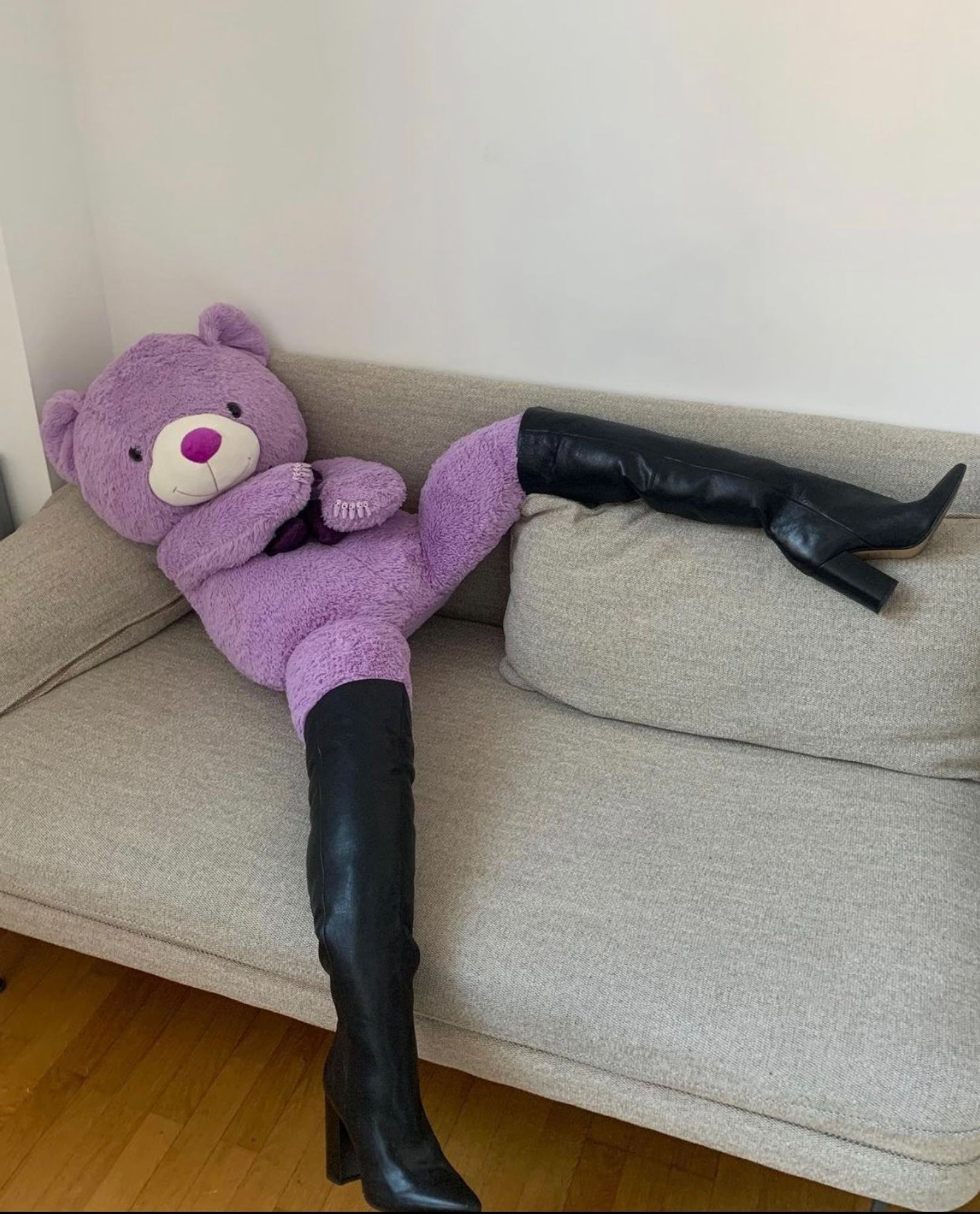 toy stuffed bear on a sofa. some leather thighboots have been arranged to give the bear the appearance of long, delicious legs. the bear is watching you seductively. turn to page (103)