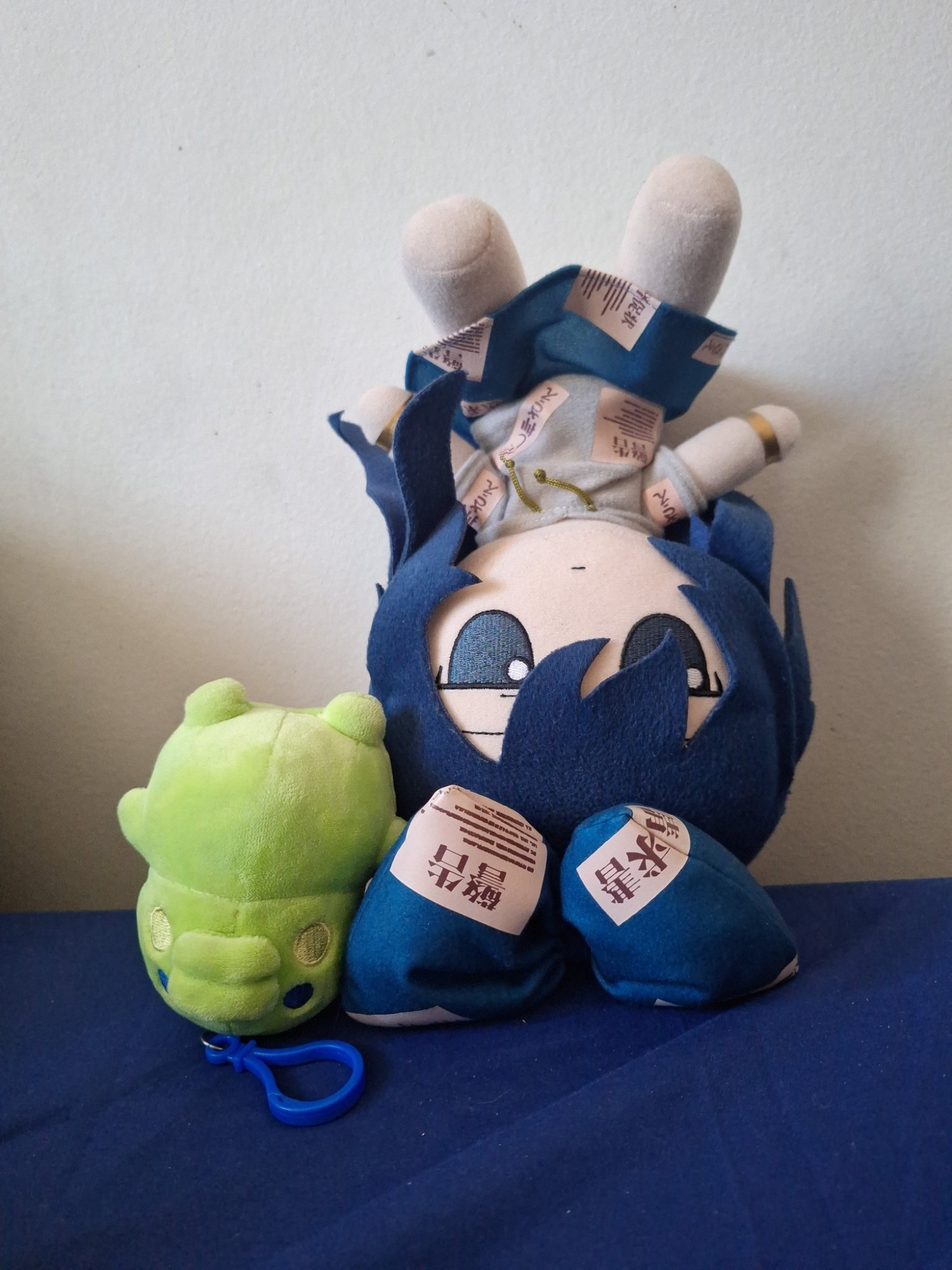 A photo of a Shion Yorigami Fumo and a Kuchipatchi plush standing upside down. Shion and Kuchipatchi are Pancake's favorite characters from Touhou and Tamagotchi respectively.