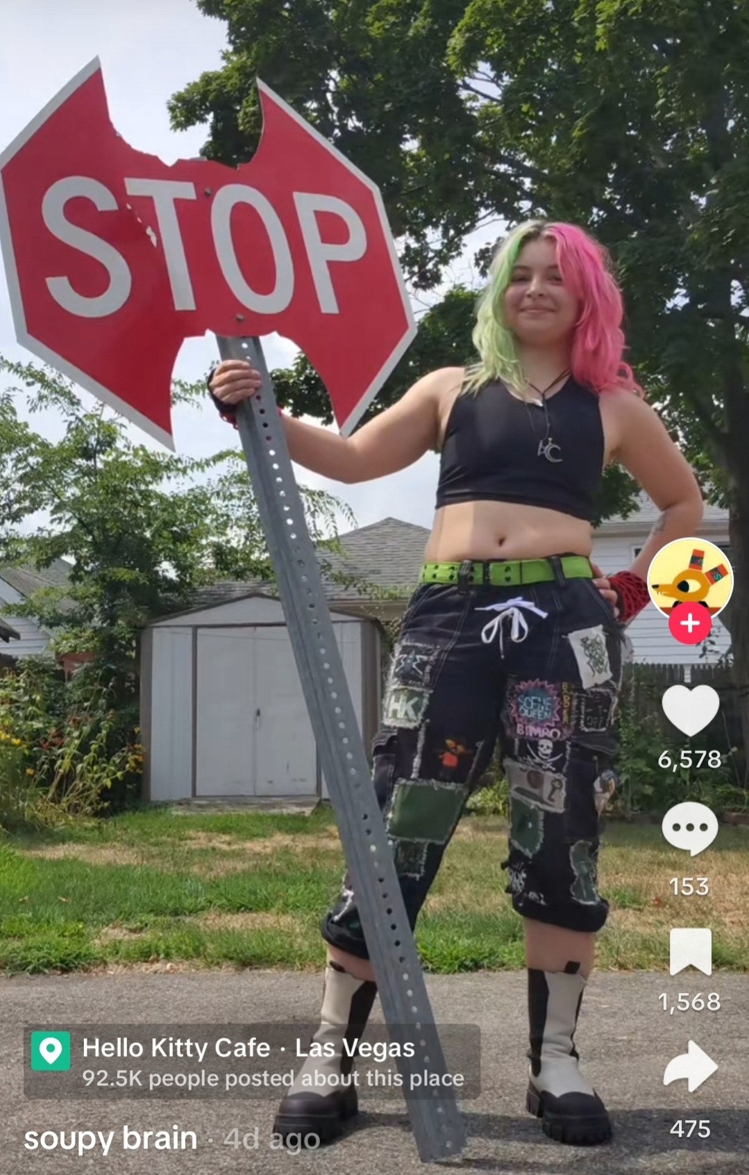 A screenshot of TikTok user Soupy Brain, a non-binary artist with pink and green hair holding a stop sign axe that is taller than them