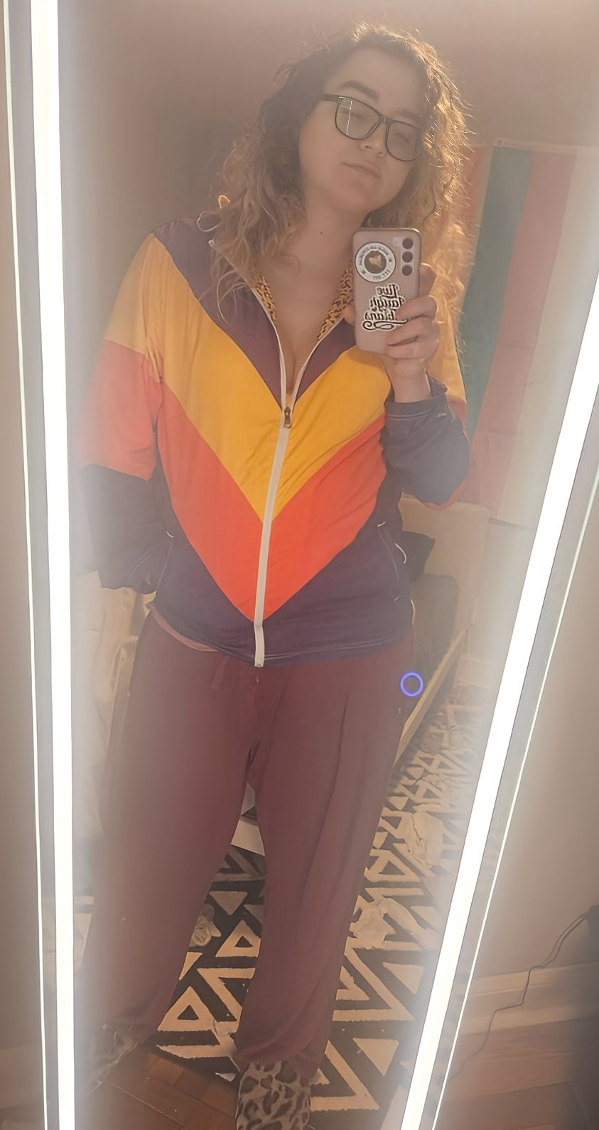 A selfie of me in a mirror featuring a purple, yellow and orange loud hoodie with leopard print inner lining, red pajama pants and leopard print slippers