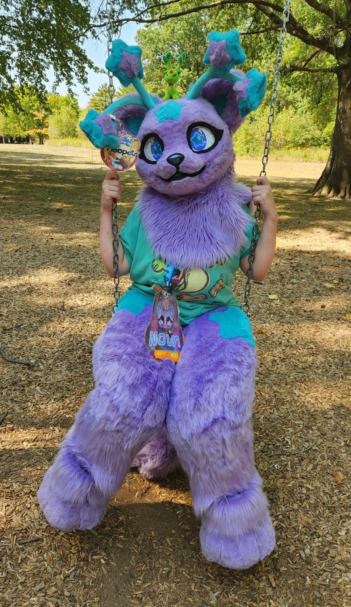 Nova Skystar fursuiter sitting on a swing at a park