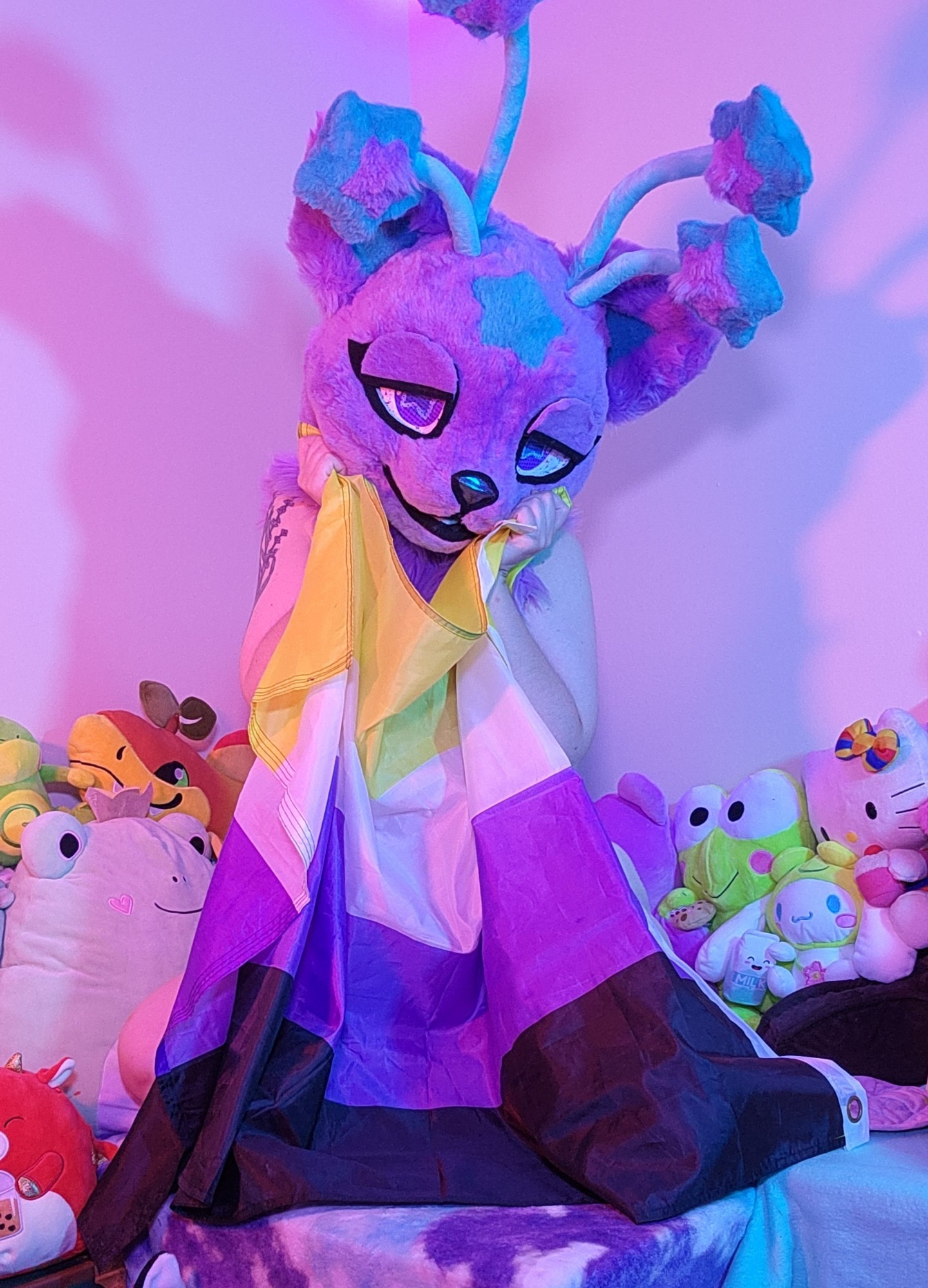 Nova Skystar fursuiter holding up a nonbinary flag over most of their body