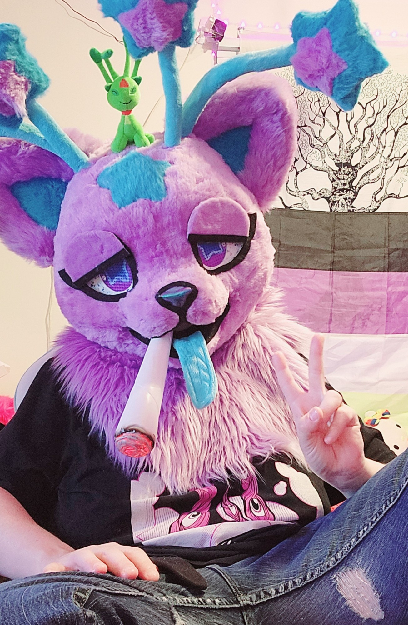 Nova Skystar fursuiter holding up a peace sign with their fingers and they have a large prop weed joint in their mouth