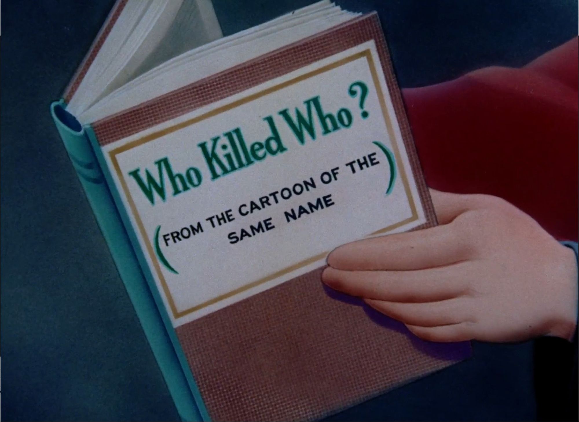 a screenshot from Tex Avery's animated short "Who killed Who" (1943) showing a hand holding a book whose title says "who killed who? (from the cartoon of the same name"