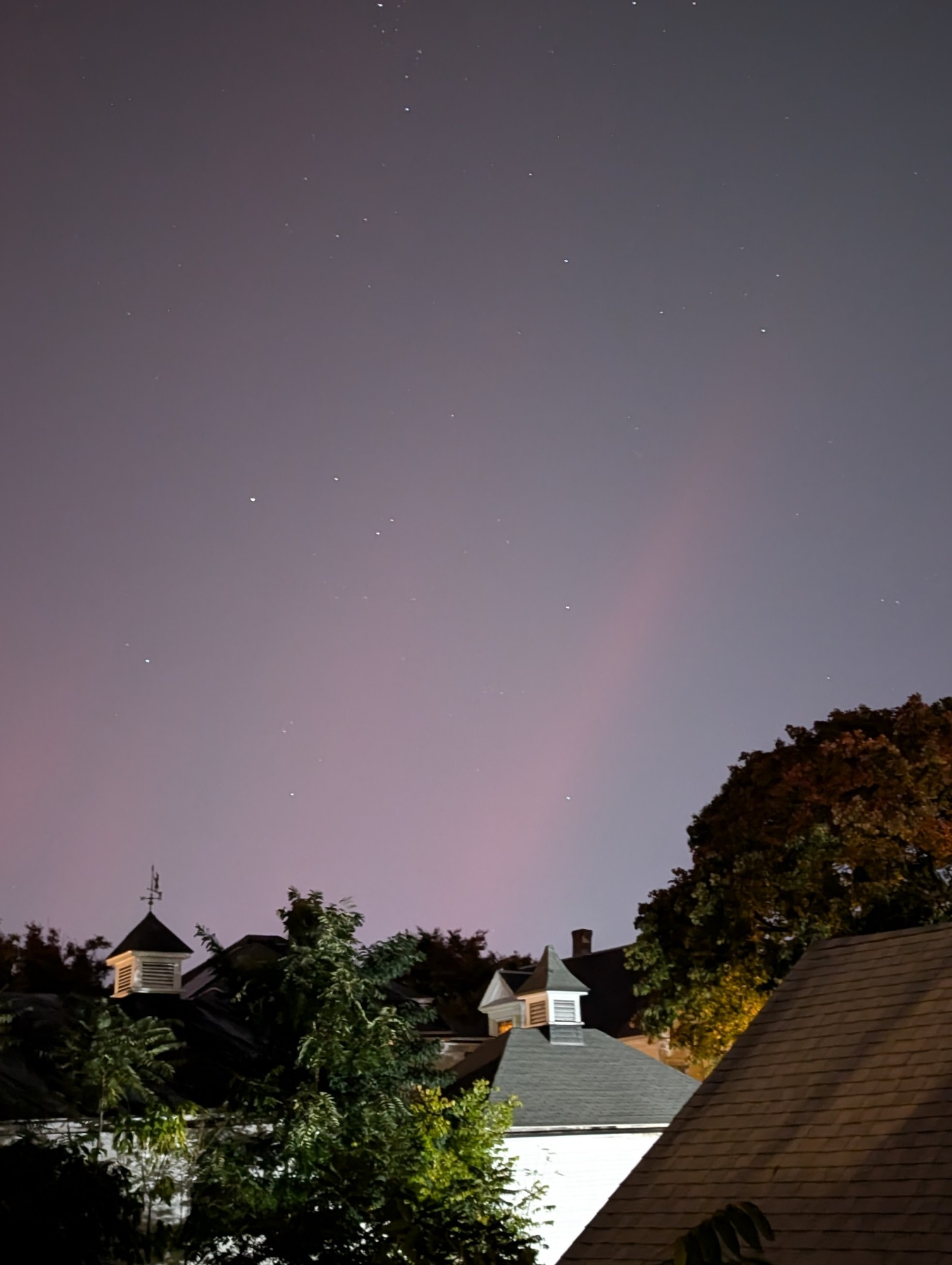 night sky over rooftops with a pink streak