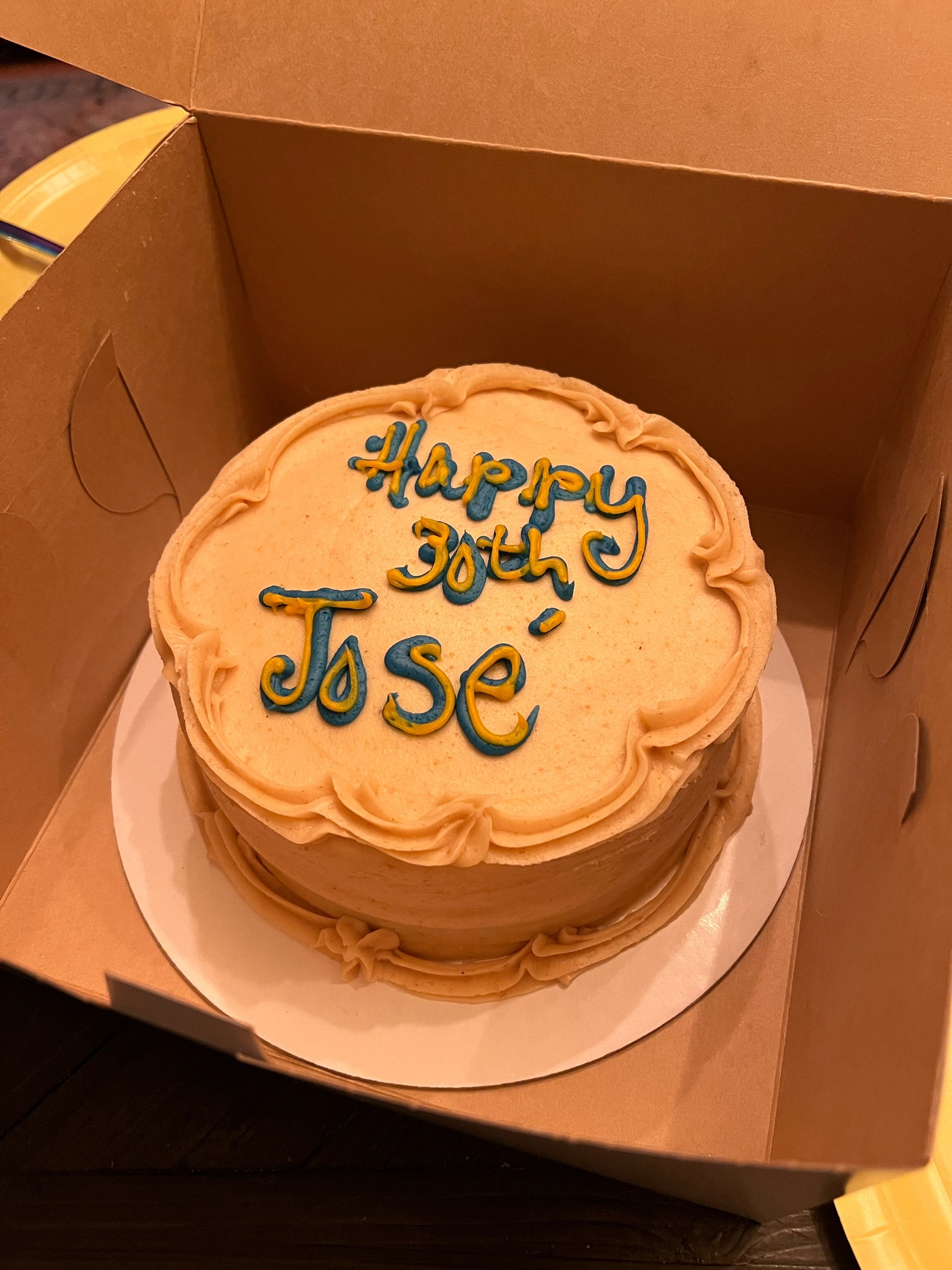 a cake in a cardboard box with "Happy 30th José" written in icing