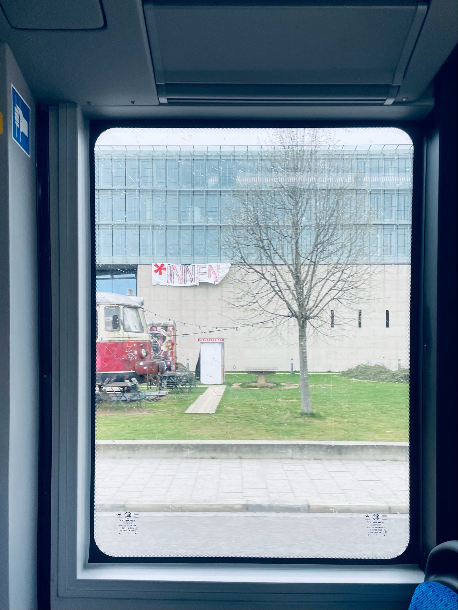 photo taken from a bus window, showing the facade of the hochschule für fernsehen und film in munich, with a large banner that states “*innen” in protest against the Bavarian government’s decision to ban gender-neutral/gender-inclusive language.