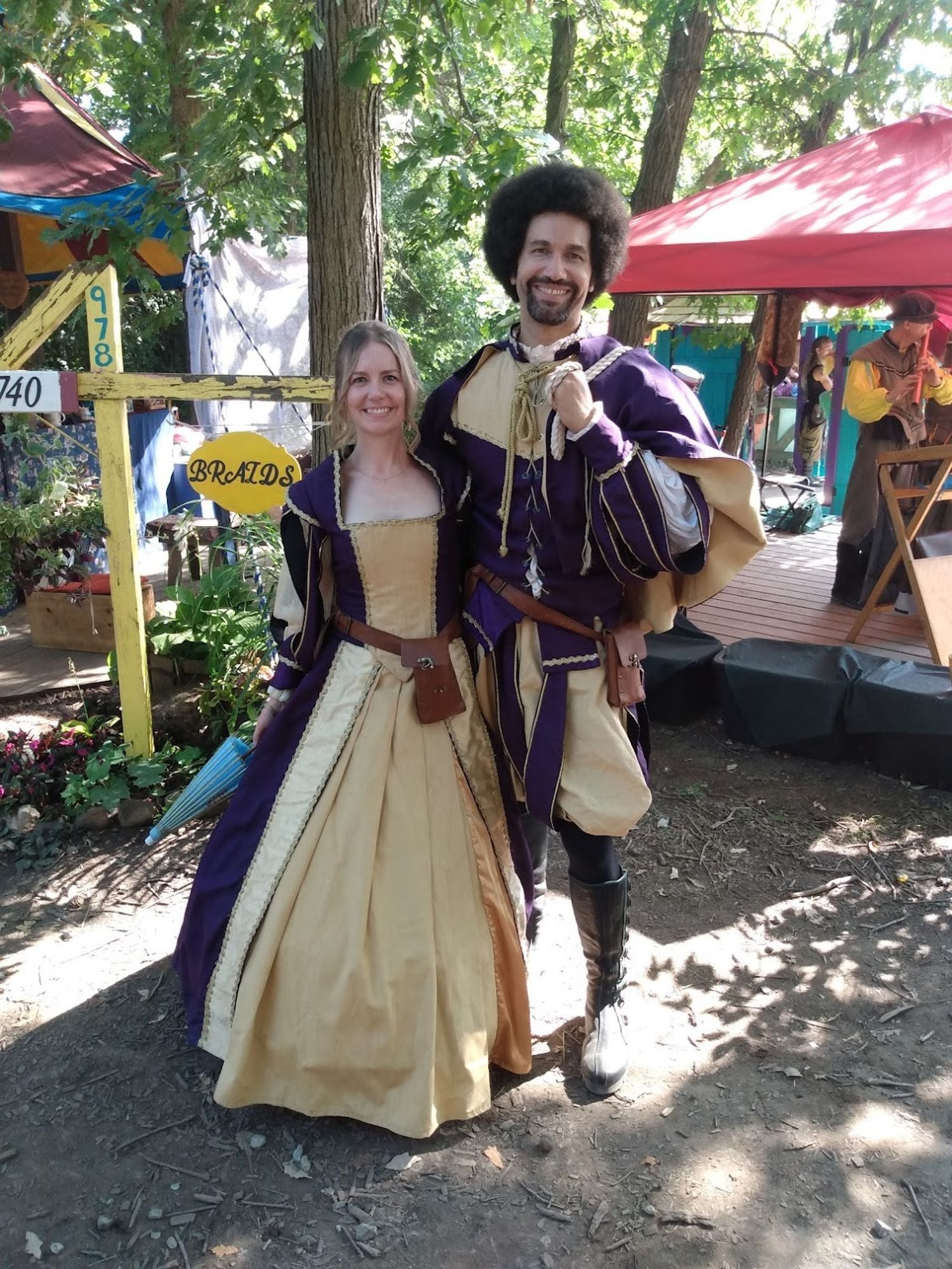 Jen Pullen and her husband in matching purple renaissance faire outfits. Distance shot.