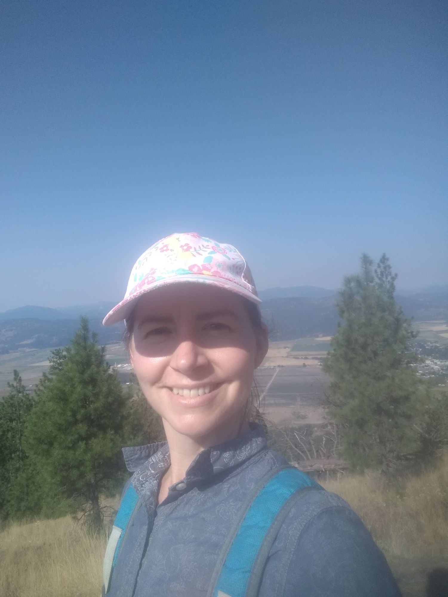 Jen Pullen smiling into camera from on top of a mountain