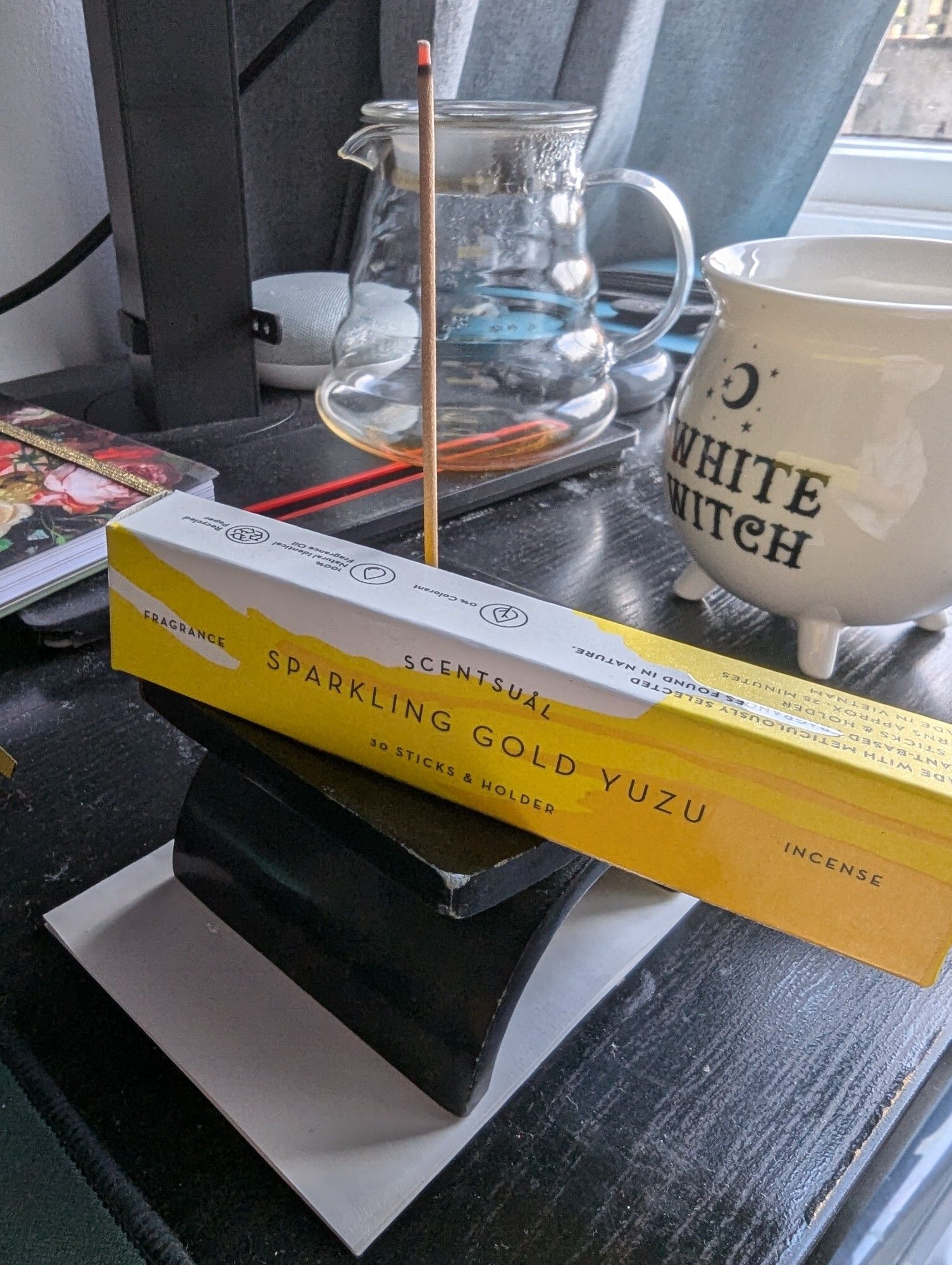 Picture of a pack of 'Sparkling Gold Yuzu' from Scentsual, alongside a lit incense stick.