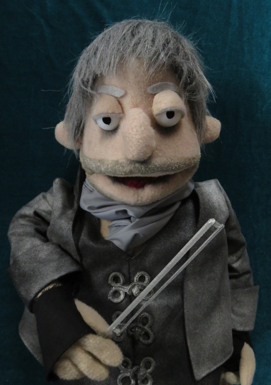 Three images of a hand-made muppet of Ned Low from Our Flag Means Death. He is grey-haired and wearing a tarnished silver suit. In the first image, he holds a silver violin bow, in the second, he is playing a silver violin and in the third, it is a close up on him and his costume.