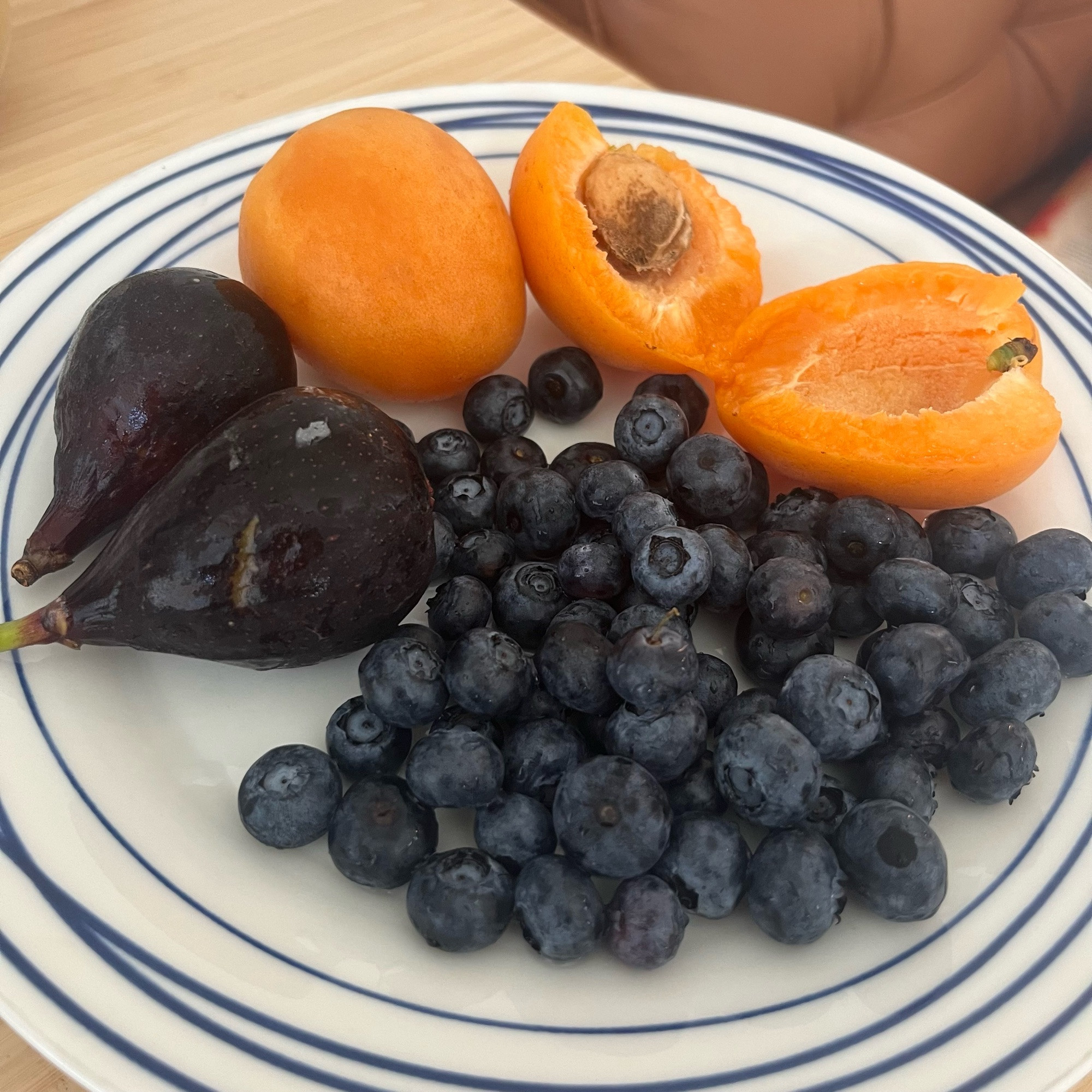 Figs, apricots, and blueberries on a blue-and-white plate