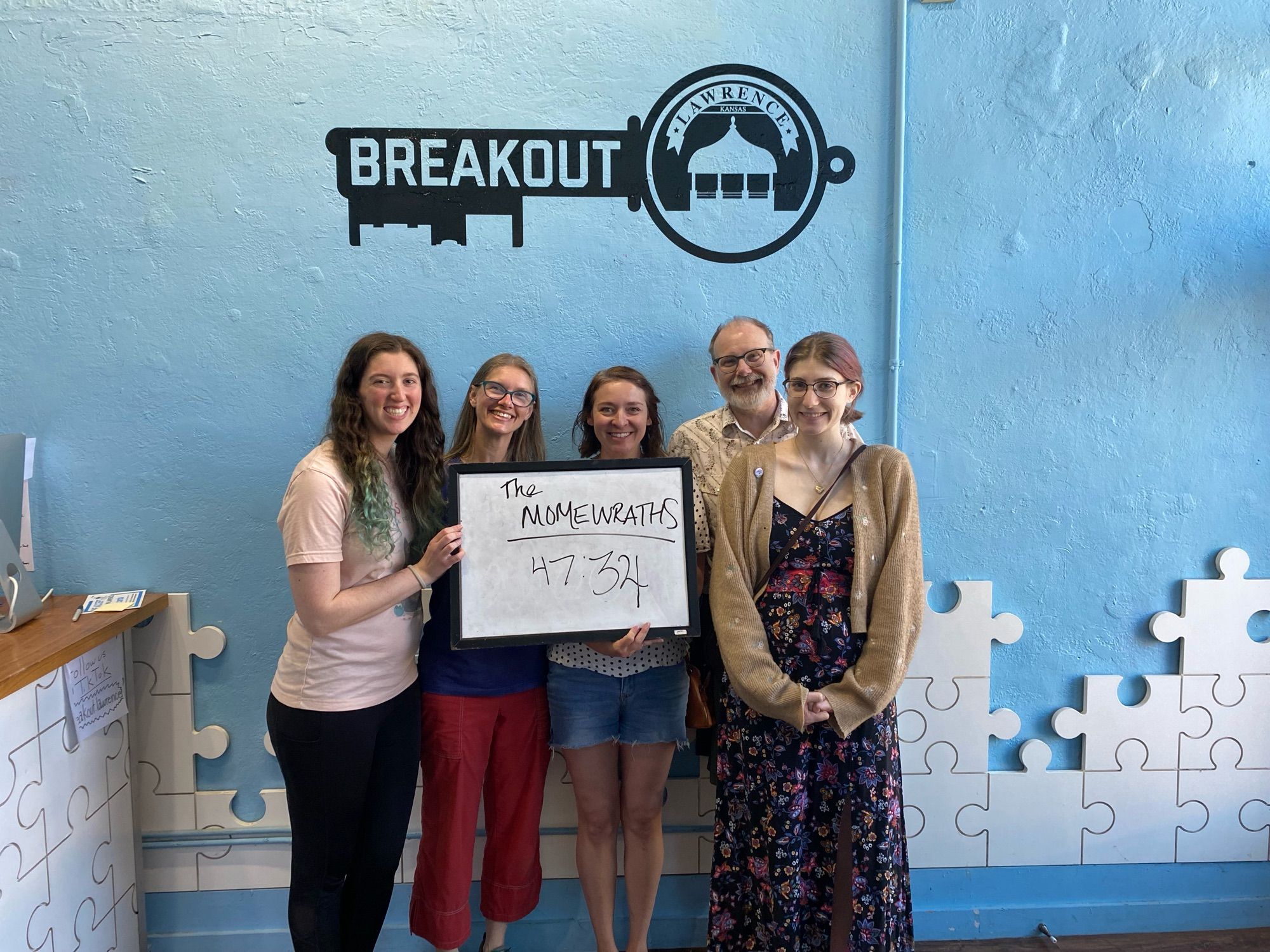 Escape room group posing in front of the Breakout sign with the time 47:34 on their whiteboard