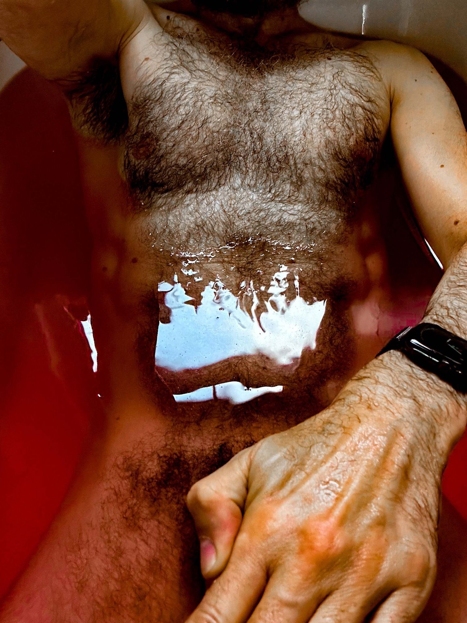 Man in bath, partial nude with hand covering crotch