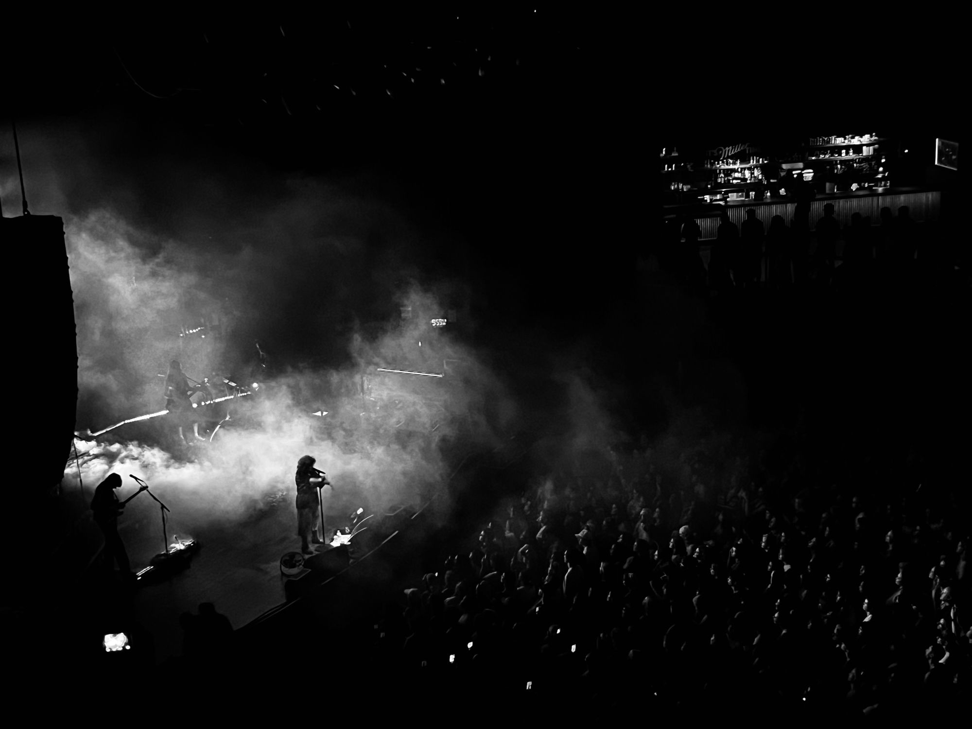 Remi Wolf playing to a venue full of people, her silhouette is visible against a background of white fog