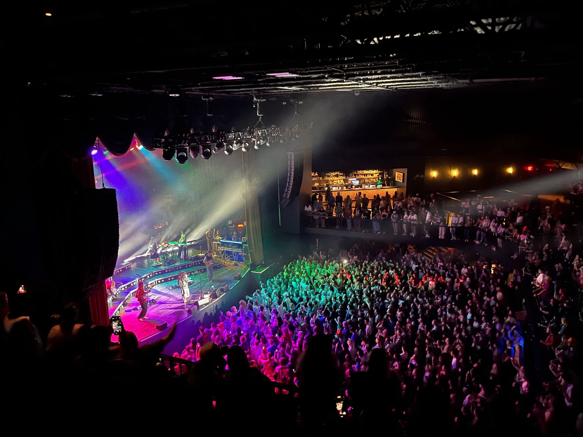 Remi Wolf playing to a venue full of of people with rainbow lighting