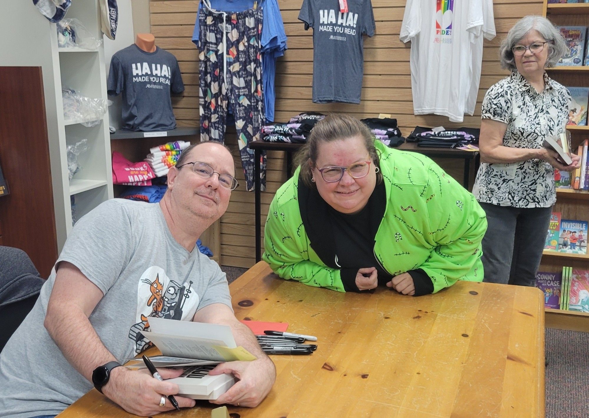 Author John Scalzi with a crazy fan in a lime-green and black sweater and a store employee.