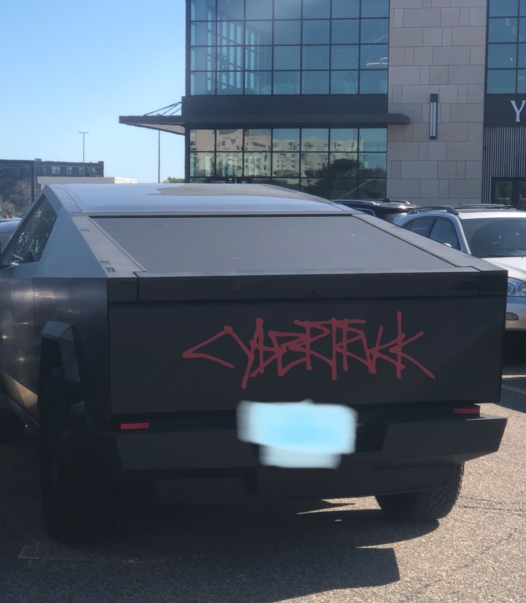 a matte black wrapped cybertruck with the dogshit spraypaint logo