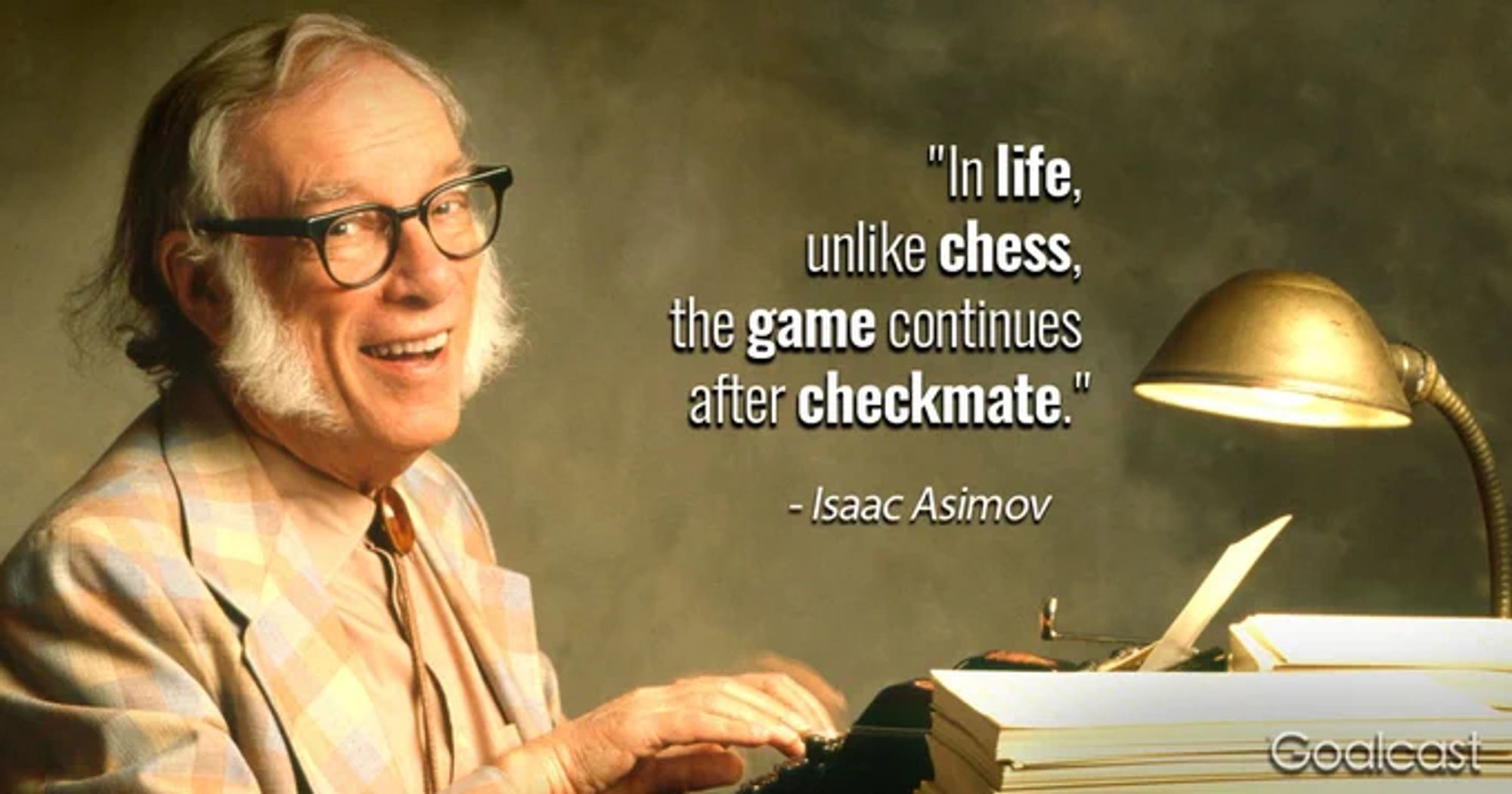 Isaac Asimov, a smiling bearded man with dark horn rim glasses, sits at a typewriter, fingers perched on keys, with a gold lamp in the foreground.

Image stamped as "Goalcast"