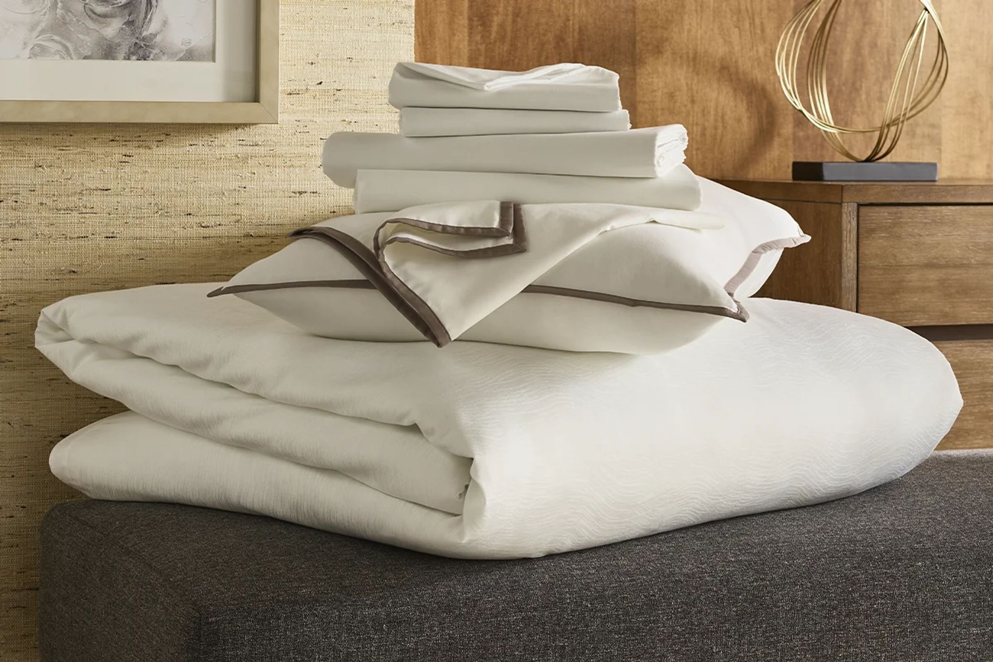 A pile of towels and bedsheets in a hotel context.  Stolen from the Westin Hotel linen collection advertisement page.  They're all white with brown edging, but pretty obviously cotton.