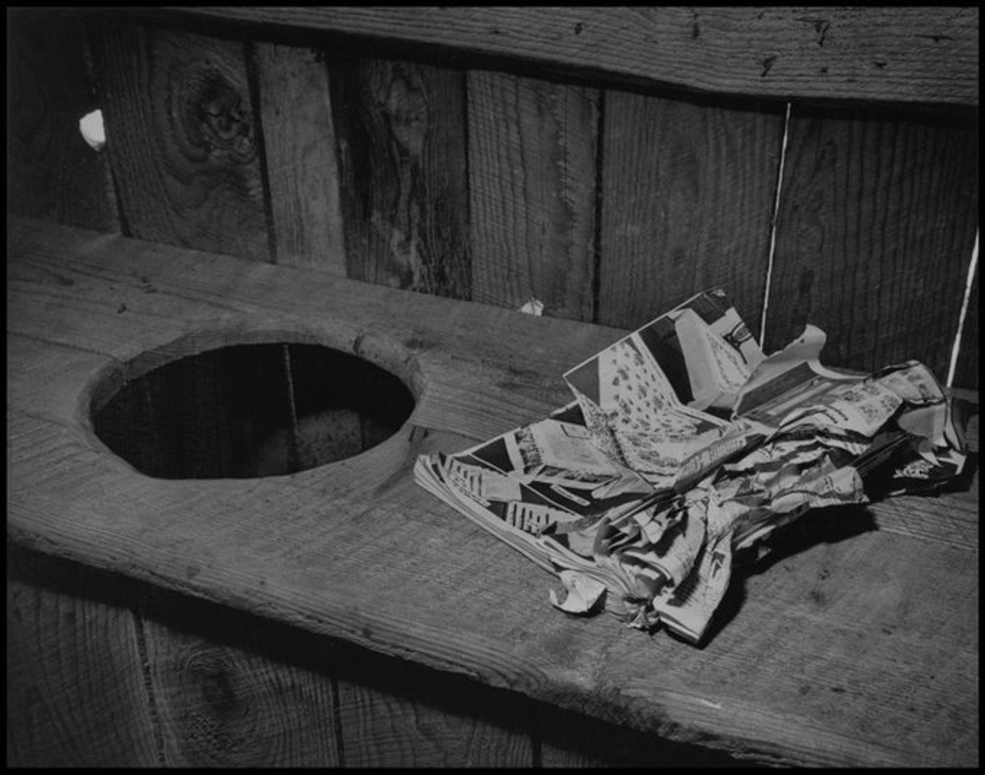 Photograph of the inside of an outhouse with a Sears, Roebucks, and Co. catalog. This negative is a copy of the original that was recreated on December 27, 1946.