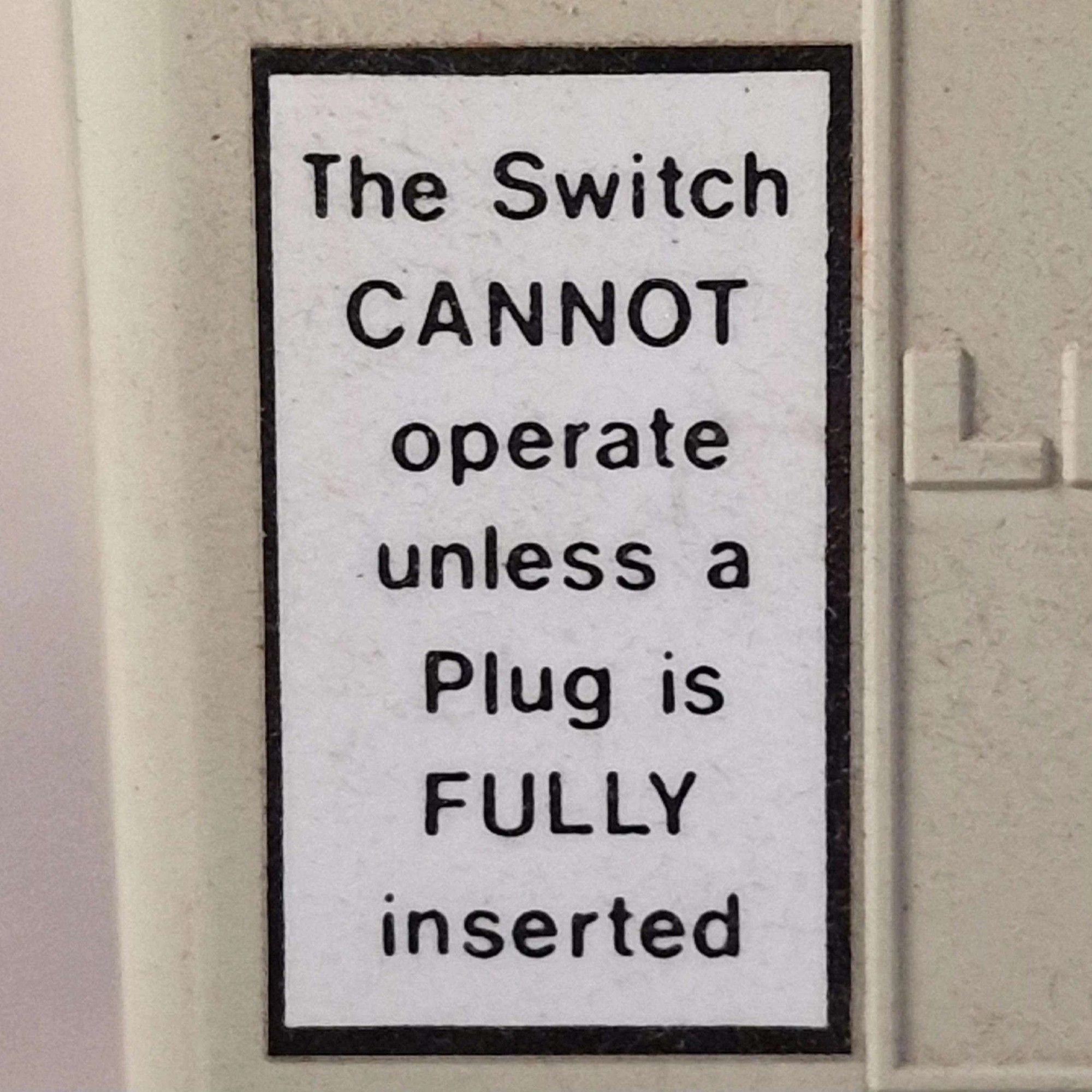 a sign on a wall, stating "The Switch CANNOT operate unless a Plug is FULLY inserted"