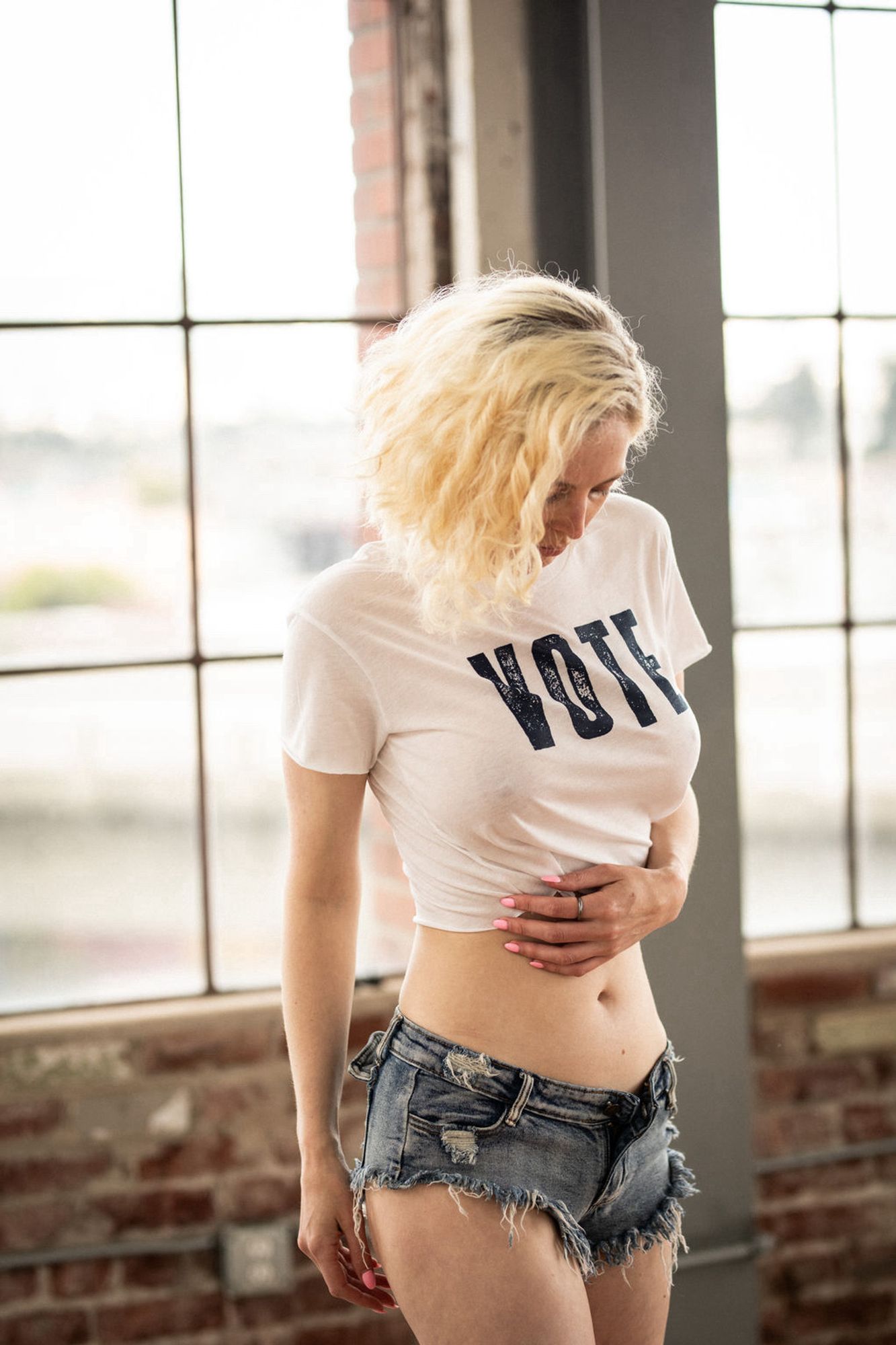 Me (white, blonde cis girl) in a thin white crop top that says VOTE in block letters and unreasonably short denim cutoffs, for democracy.