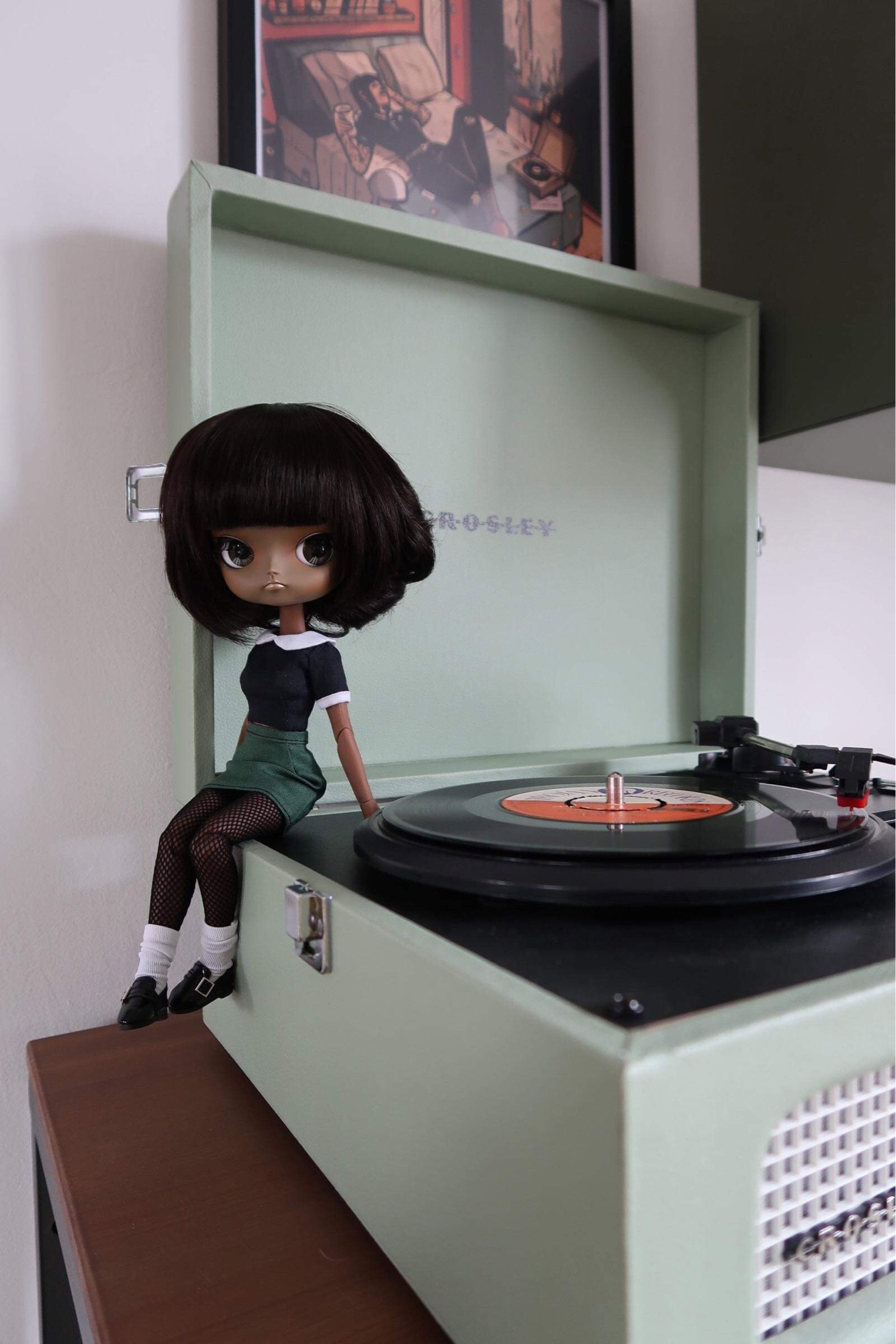 Poupée Dal à la peau noire, avec un style 60s, assise sur un tourne-disque