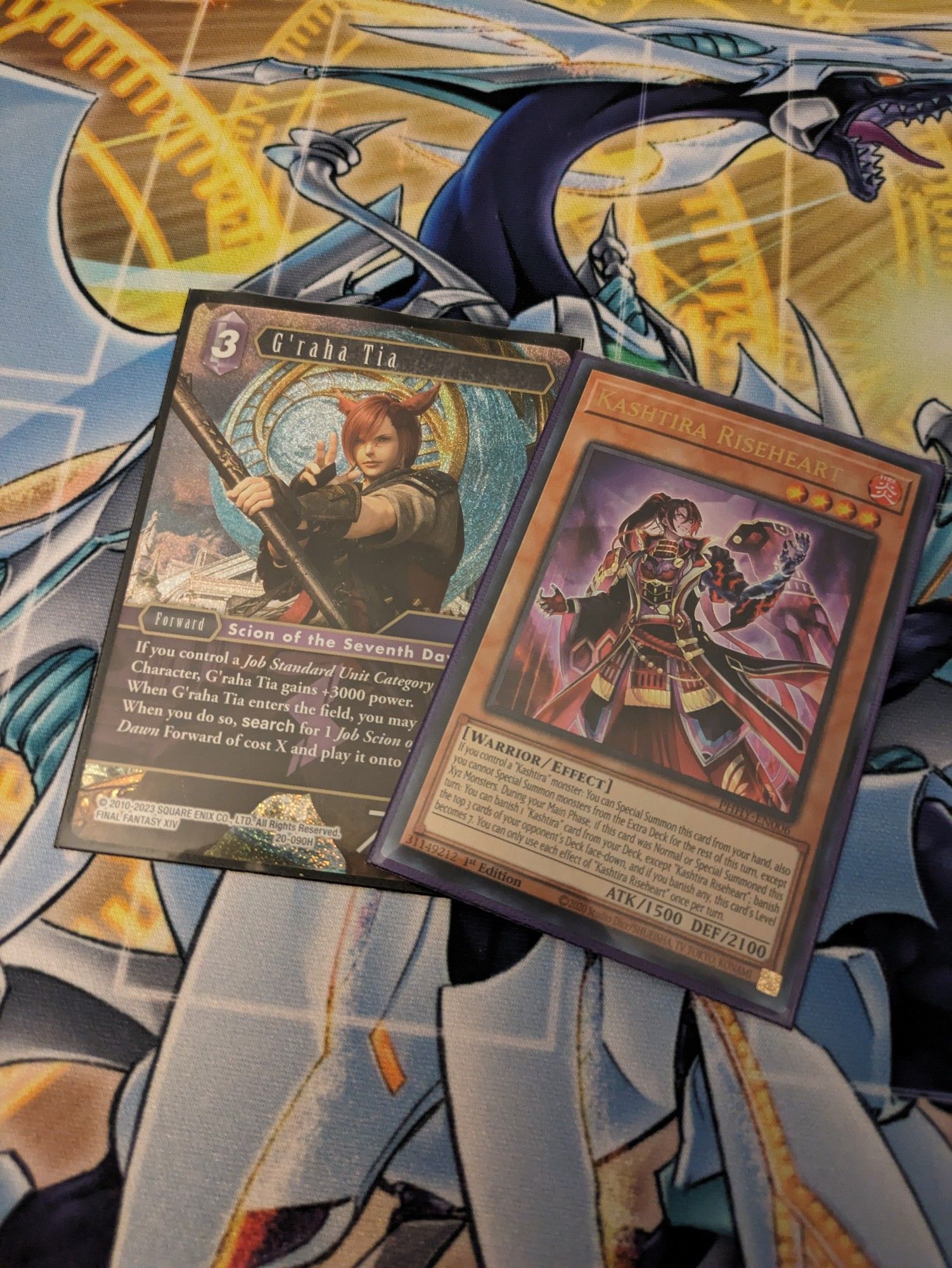 A copy of the yugioh card Kashtira Riseheart and a copy of the Final Fantasy TCG card G'raha Tia