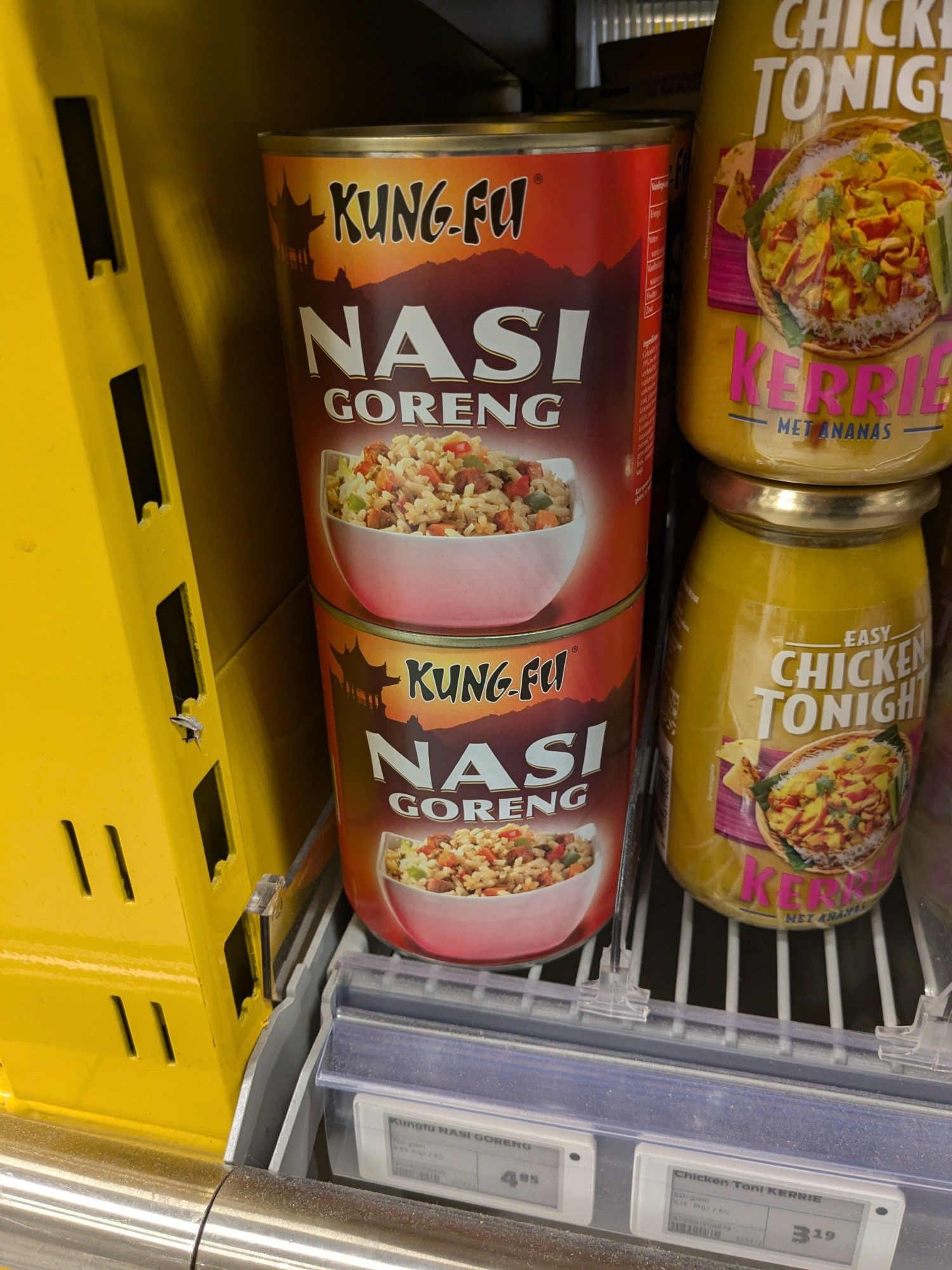 A canned friend rice in a supermarket shelf. The can had the brand Kung-Fu with a large text that says nasi goreng.