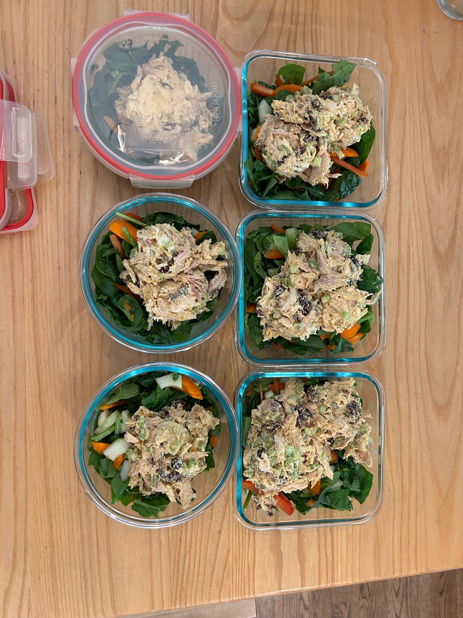 6 glass containers with salad and large scoops of chicken salad on them