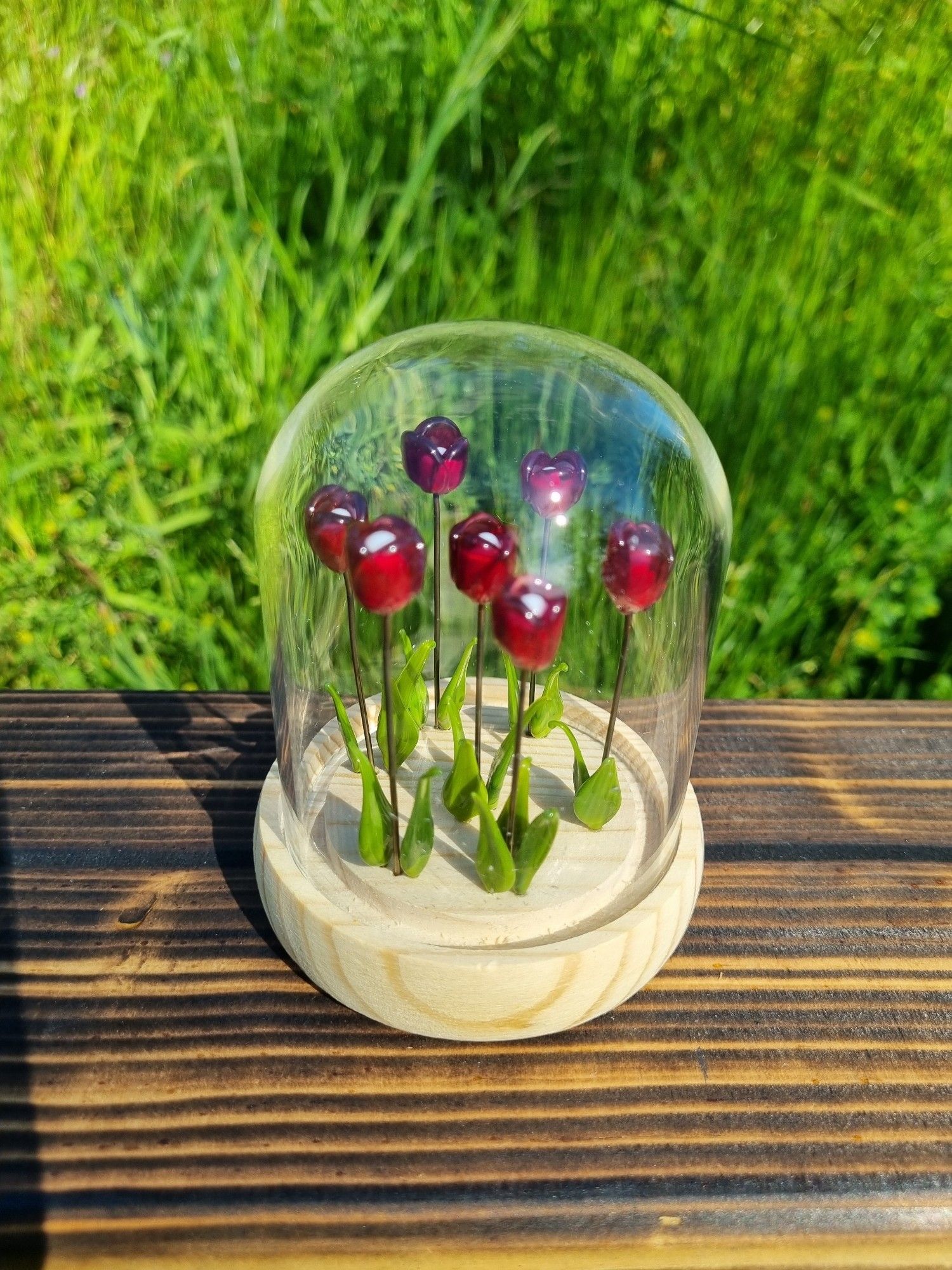 Petite cloche en verre avec des tulipes et herbes en verre