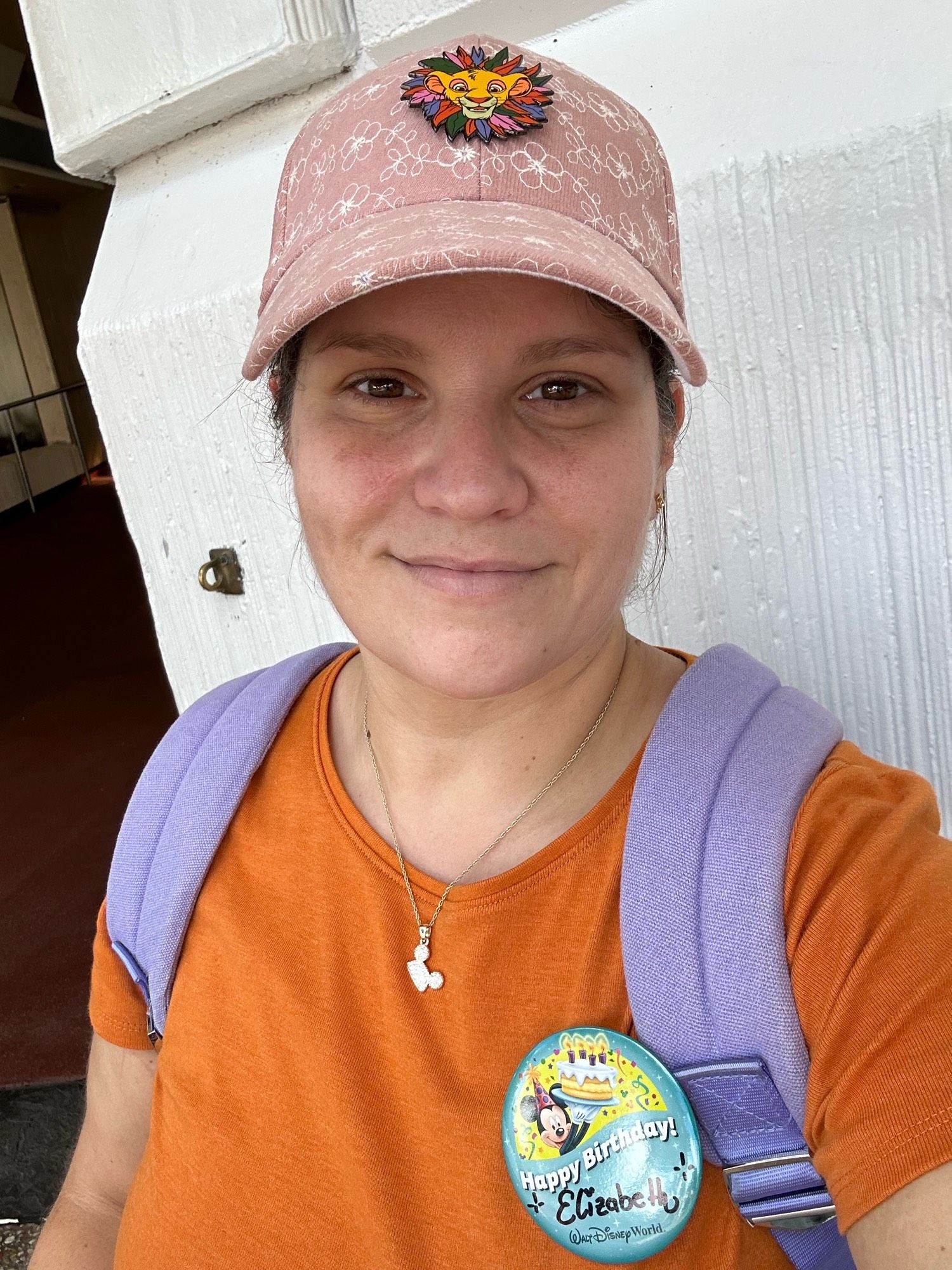 Me in an orange shirt and WDW birthday pin. My hat has a Simba pin on it