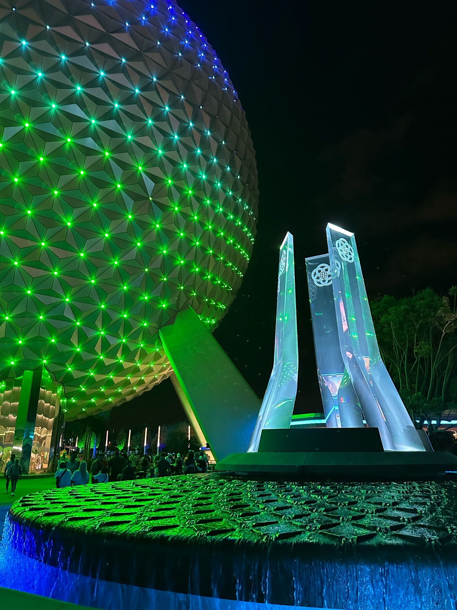 Spaceship earth lit up in green with the new fountain sculpture