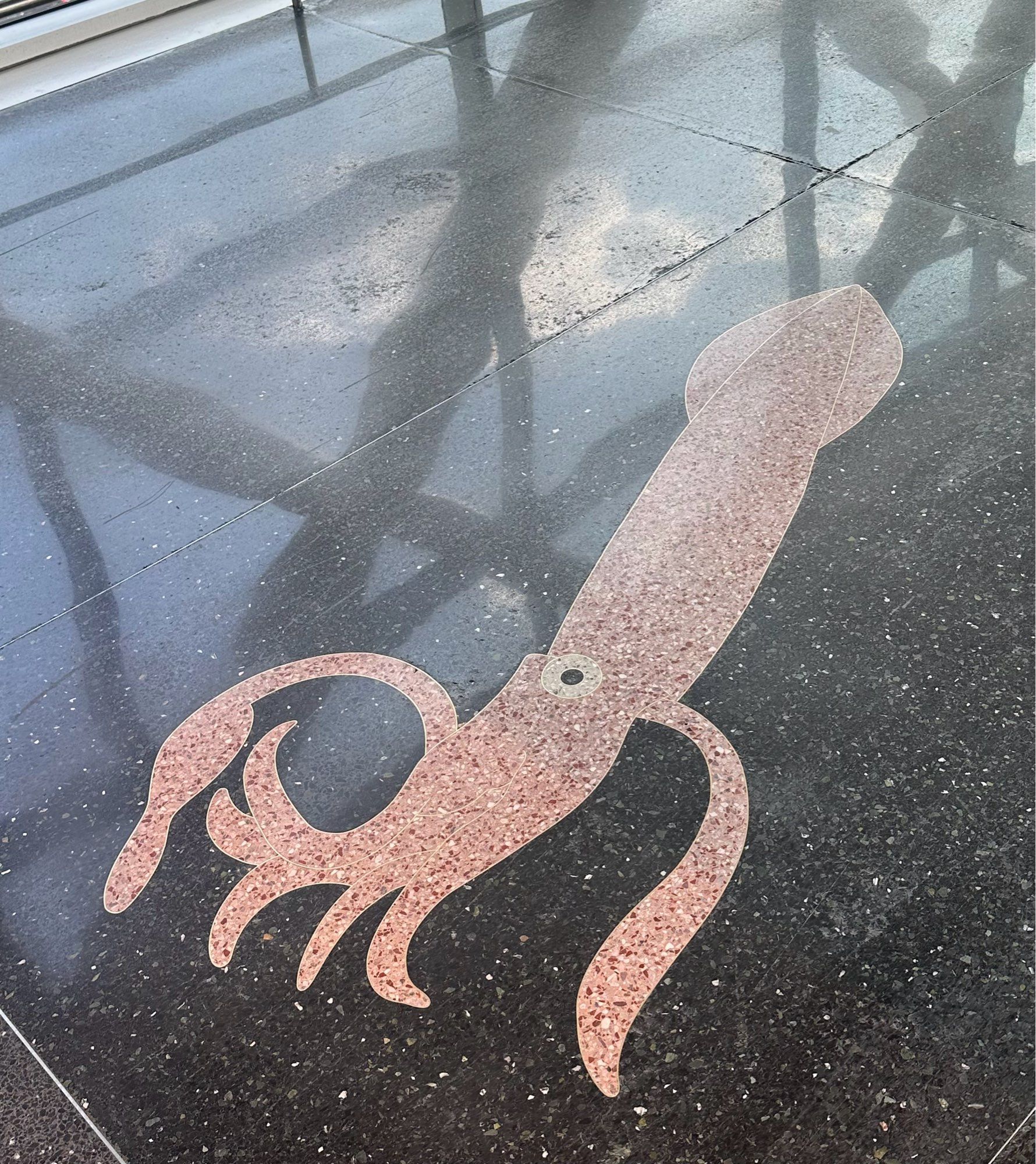 A pink squid as part of the floor of an airport walkway.