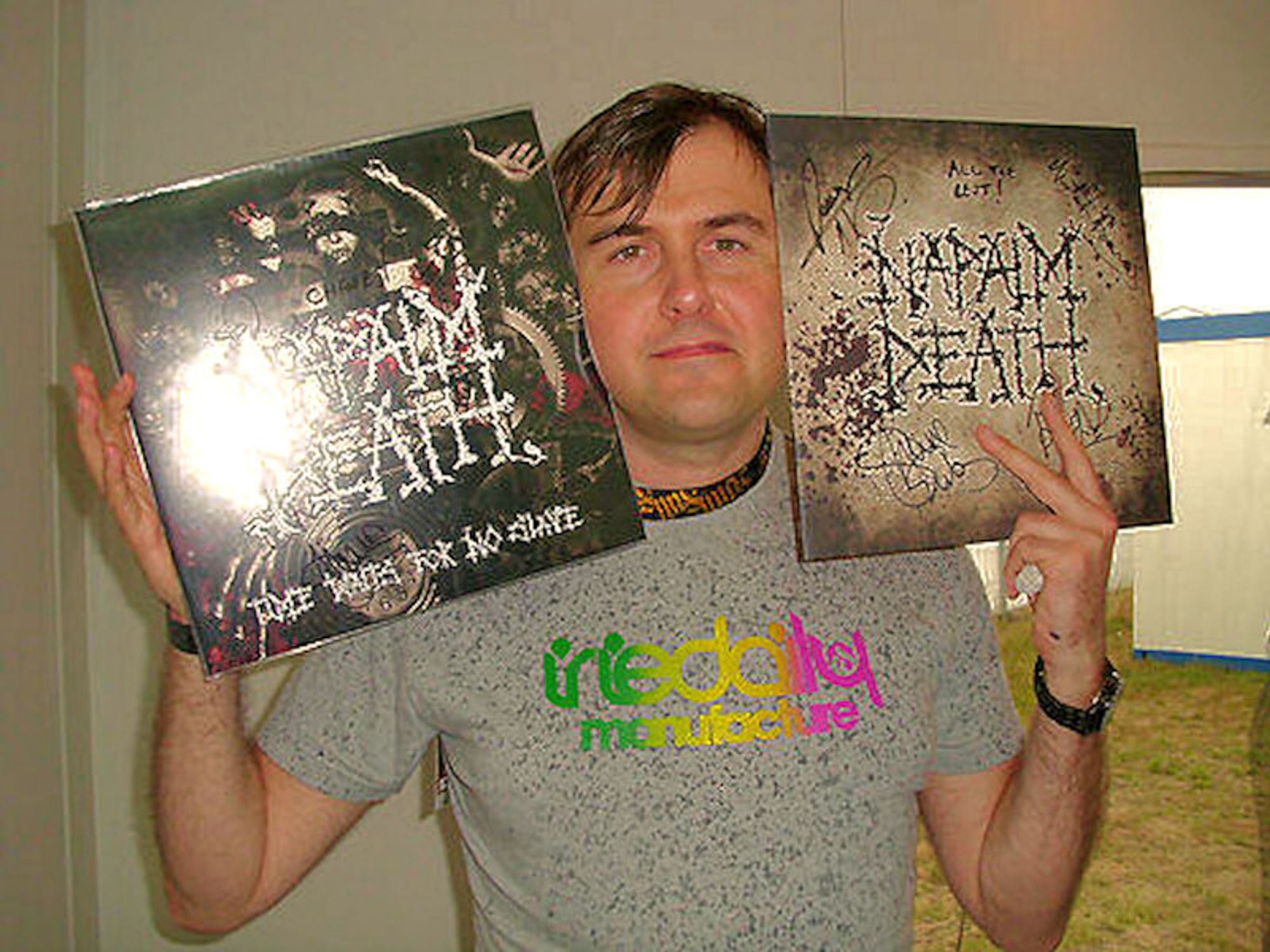 Barney Greenway of Napalm Death holding up two signed versions of their LP "Time waits for no slave"