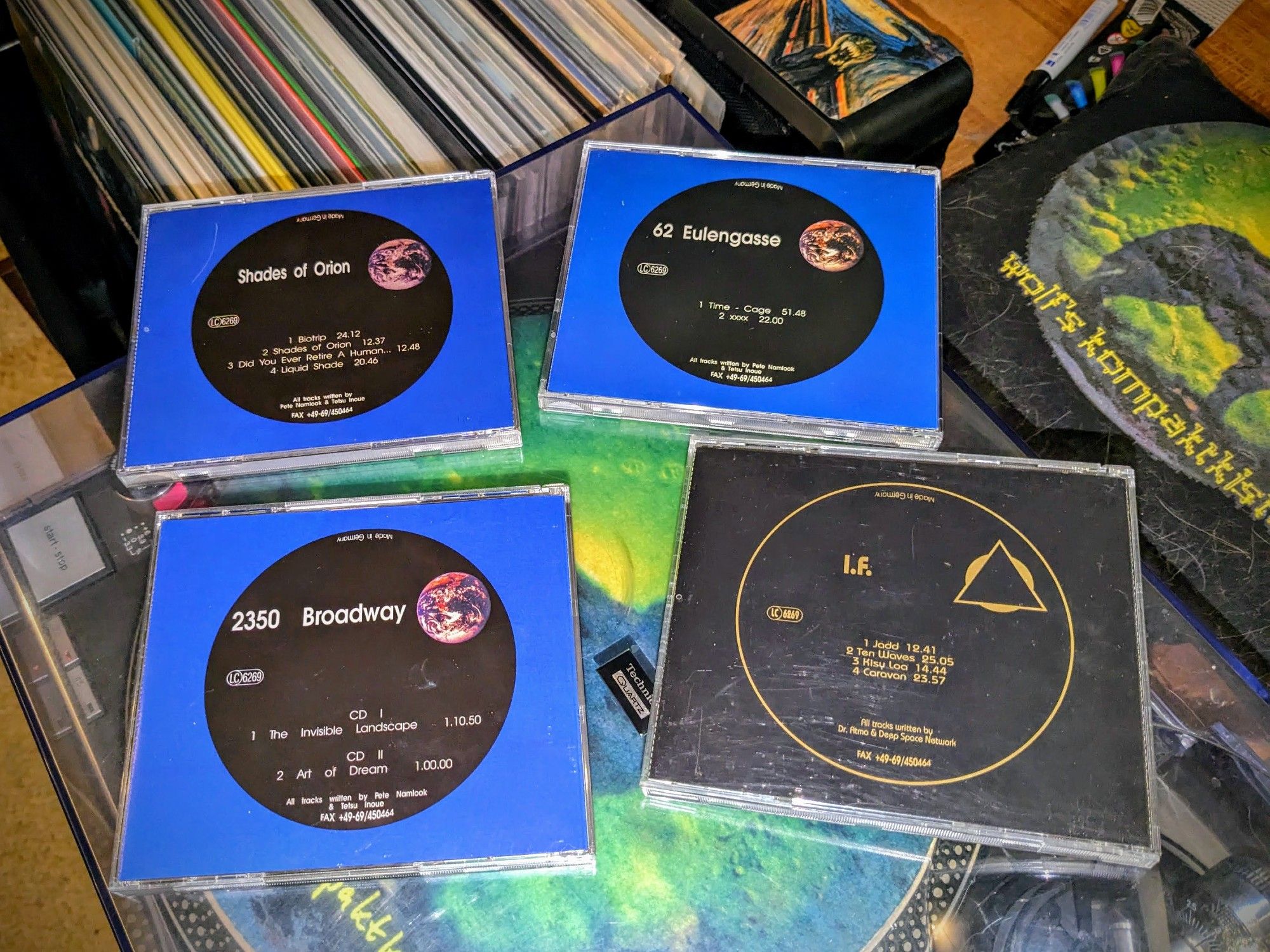 four Fax cd jewelcase back-covers laid out on the Technics turntable: Shades of Orion PW09, 62 Eulengasse PW21, 2350 Broadway 2 PW12, in their blue design with a black circle, and the black I.F. PS 08/33.