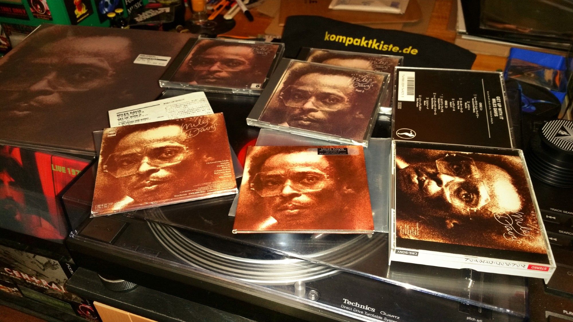 various cd versions and an lp of "Miles Davis - Get Up With It" arranged on the turntable