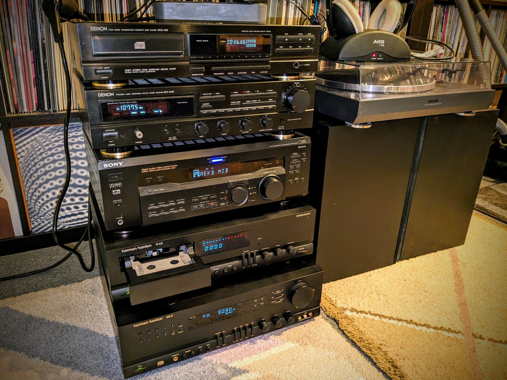 some hifi gear, switched on, twoered in two piles on the carpet placed in front of the record collection wall: 
harman/kardon AVR 21 receiver, 
harman/kardon TD 420 tape deck with horizontal motorized tape tray, 
Sony STR-DE445 receiver, 
Denon DRA-435R receiver, 
Denon DCD-480 CD-Player, 
AKG T 912 wireless headphones, 
Philips FP 930 Vinyl Record Player, 
and a pair of MIssion Cyrus 781 loudpeakers.