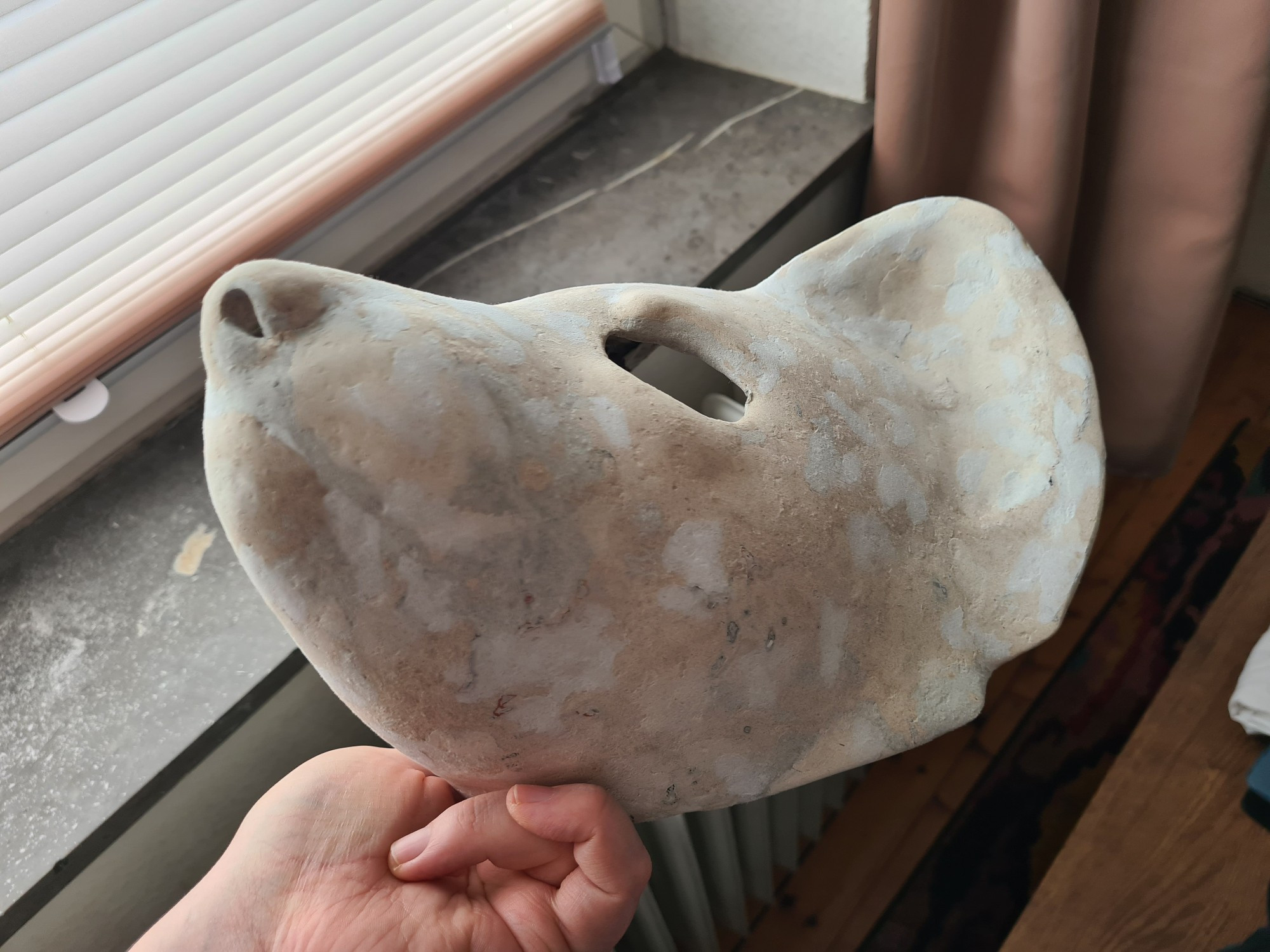 A semi-realistically sculpted wearable mask of a pine marten, made out of chicken wire and cardboard clay. The surface is mottled with different types of ever finer grained cardboard clay. View of the lower left side.