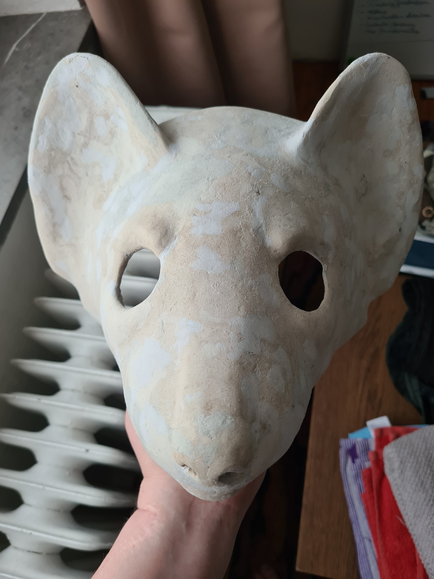 A semi-realistically sculpted wearable mask of a pine marten, made out of chicken wire and cardboard clay. The surface is mottled with different types of ever finer grained cardboard clay. View of the top-front.