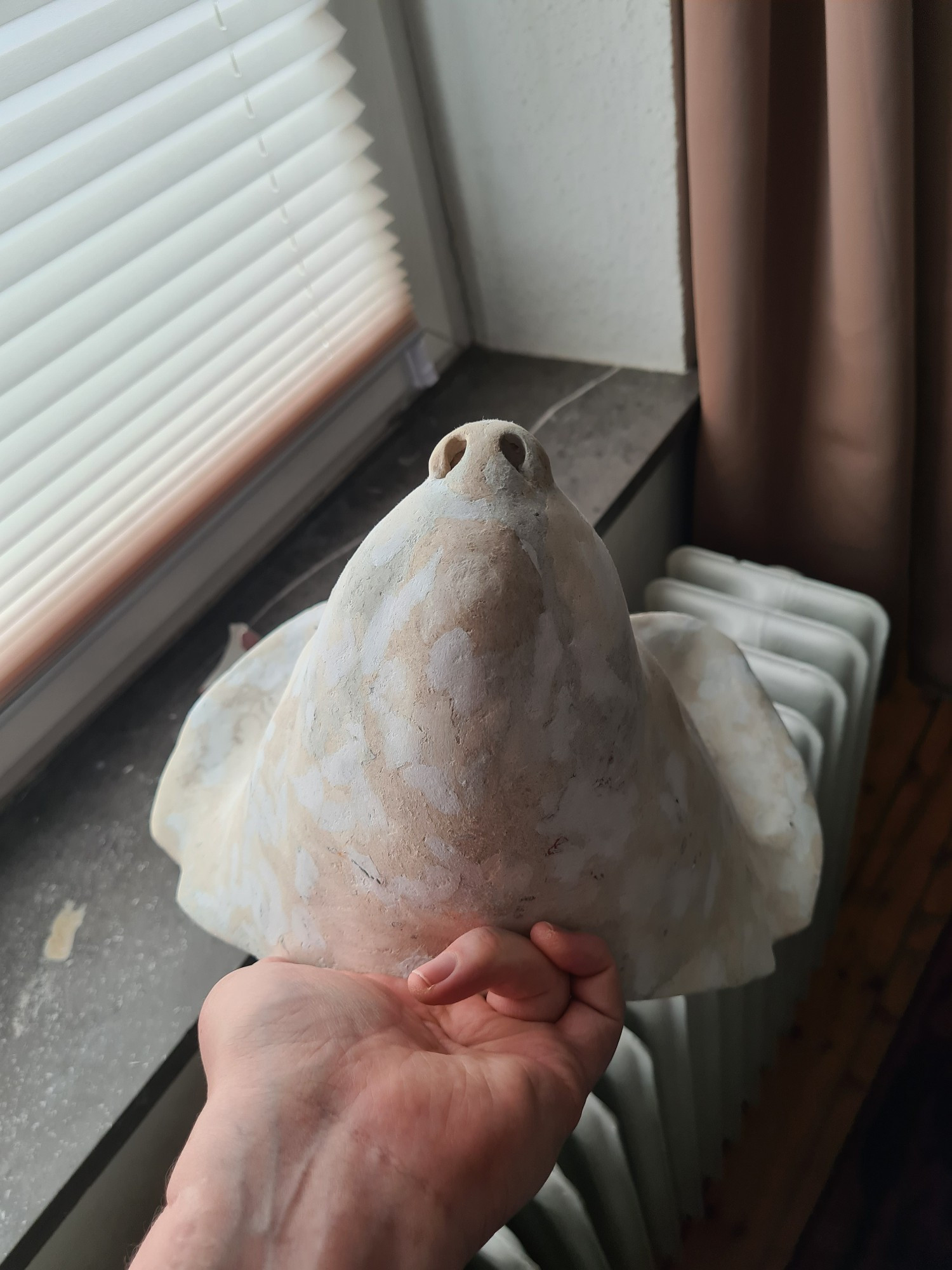 A semi-realistically sculpted wearable mask of a pine marten, made out of chicken wire and cardboard clay. The surface is mottled with different types of ever finer grained cardboard clay. View of the bottom.