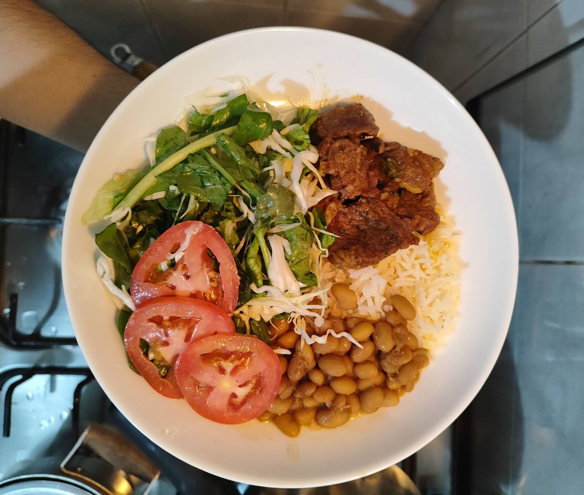 Prato de comida com arroz, feijão, carne de panela e salada de vegetais: alface, rúcula, repolho e tomate.