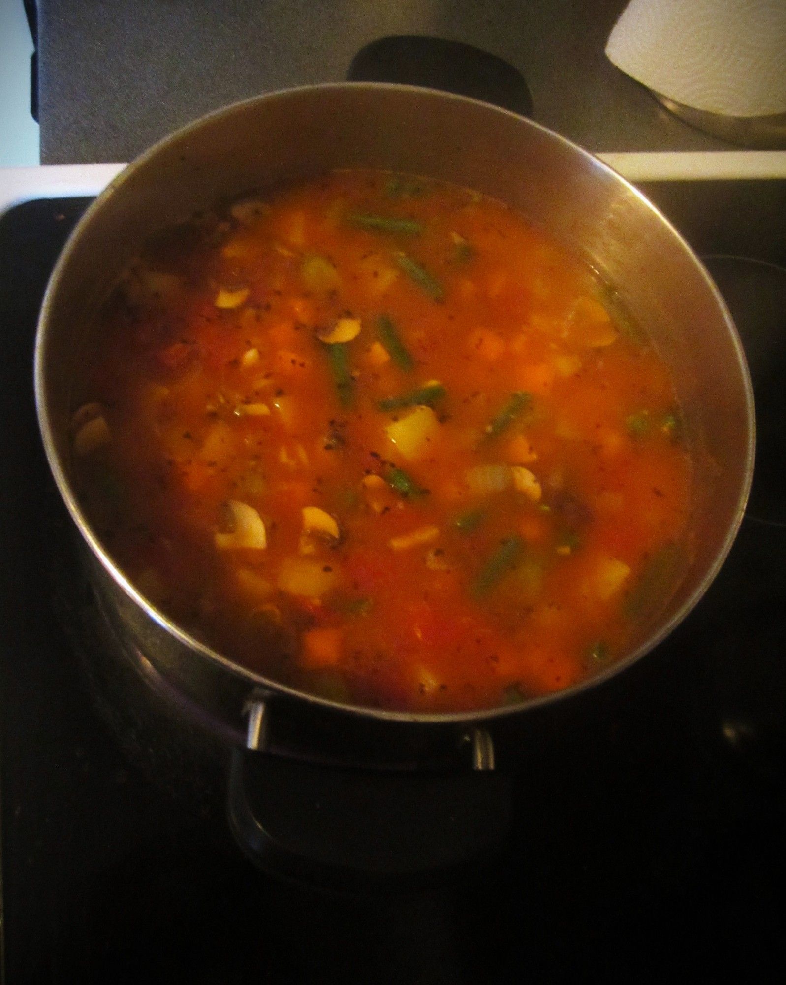 A photo of a pot of tomato based vegetable pasta soup.