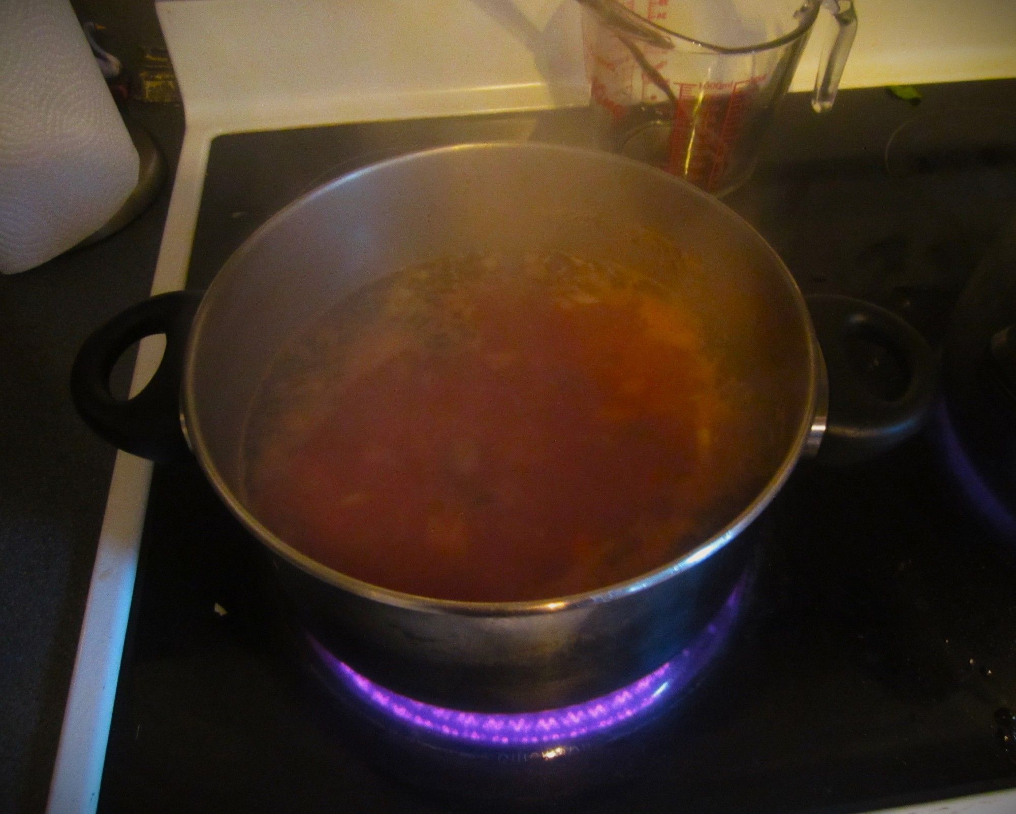 A photo of red soup stock bubbling on the stove.