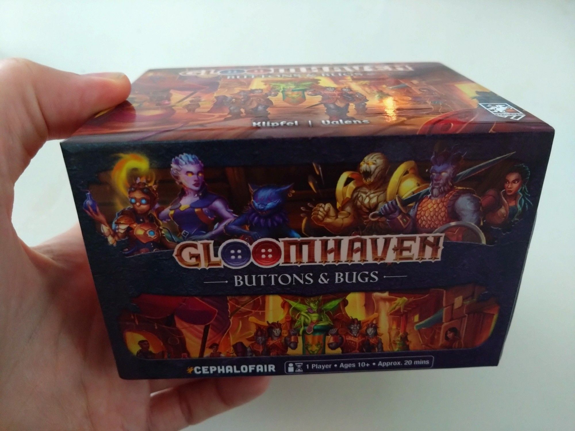 A picture of a hand holding the small Gloomhaven Buttons&Bugs box