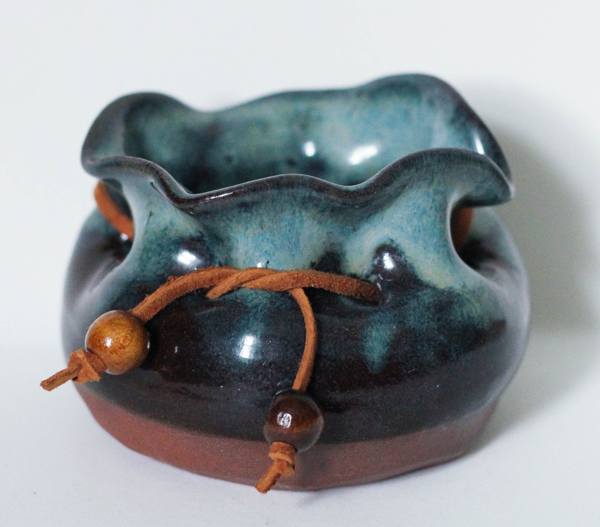 a little blue dish shaped like a drawstring satchel, complete with leather cord and wooden beads threaded through the holes