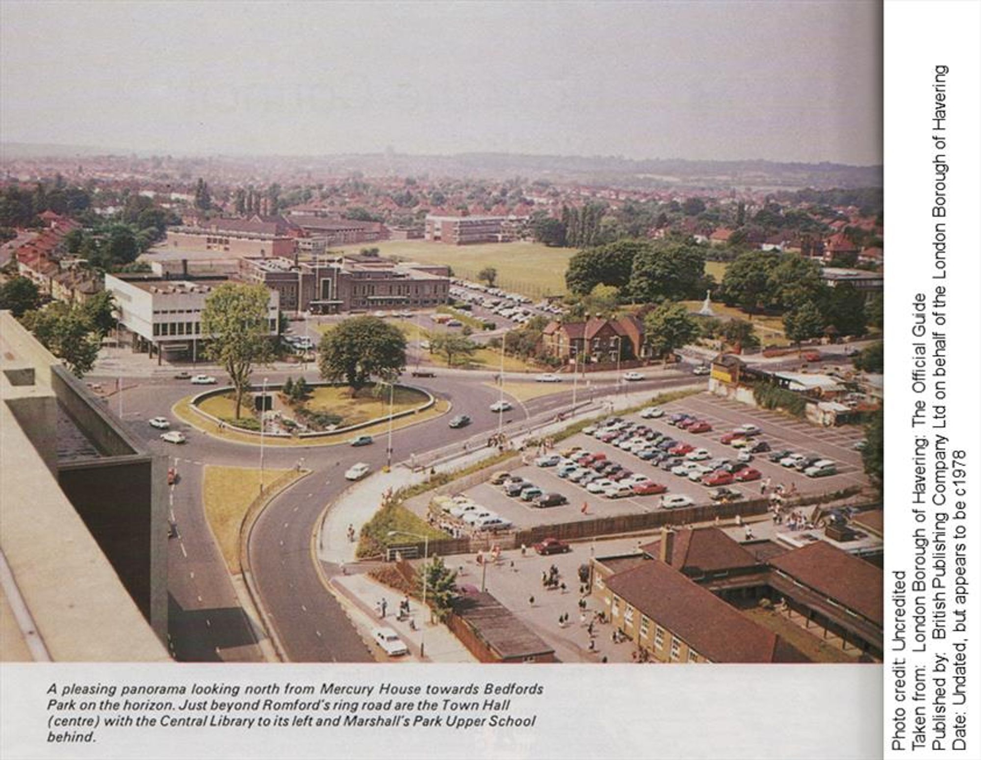 A colour photo of central Romford. The caption reads: A pleasing panorama looking north from Mercury House towards Bedfords Park on the horizon. Just beyond Romford's ring road are the Town Hall (centre) with the Central Library to its left and Marshall's Park Upper School behind.

Photo credit: Uncredited
Taken from: London Borough of Havering: The Official Guide
Published by. British Publishing Company Ltd on behalf of the London Borough of Havering Date: Undated, but appears to be c.1978