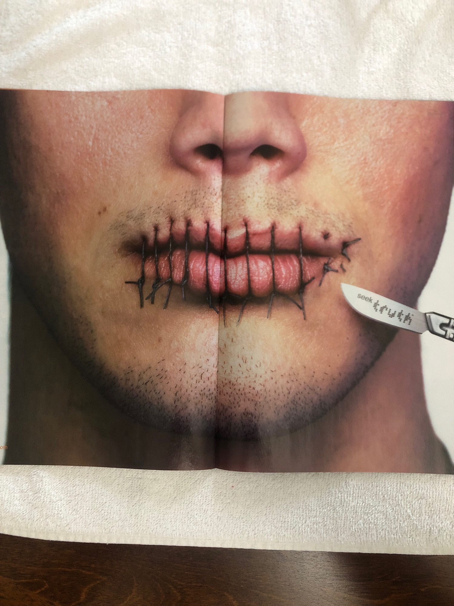 Ad in a comic for Truth, an anti-tobacco campaign. Two page ad, a close up on the bottom half of a face. The lips are sewn together, a scalpel hovers near the mouth - says “seek Truth” on the blade.